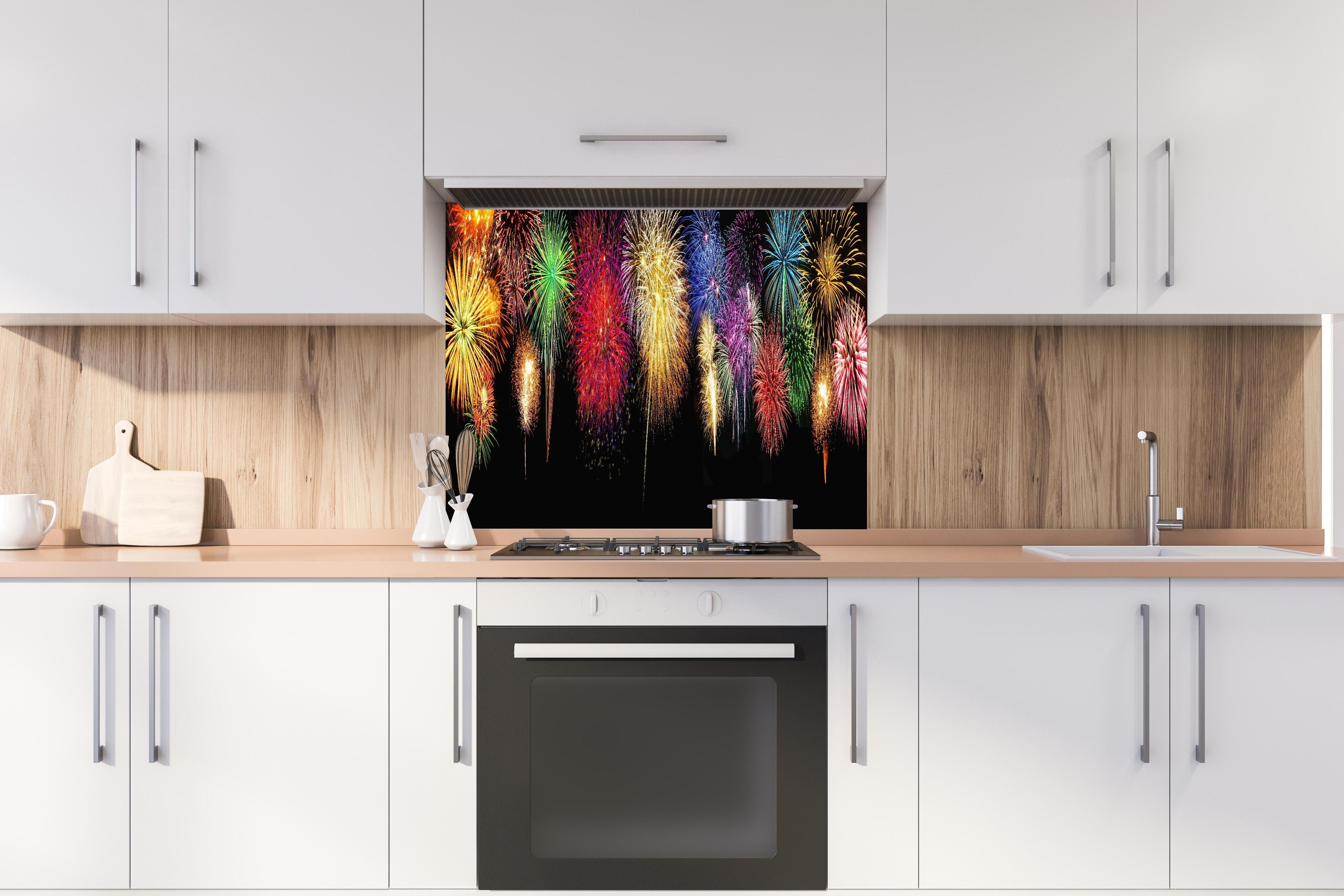 Spritzschutz - Panoramisches Silvesterfeuerwerk in leuchtenden Farben hinter einem Cerankochfeld zwischen Holz-Kochutensilien