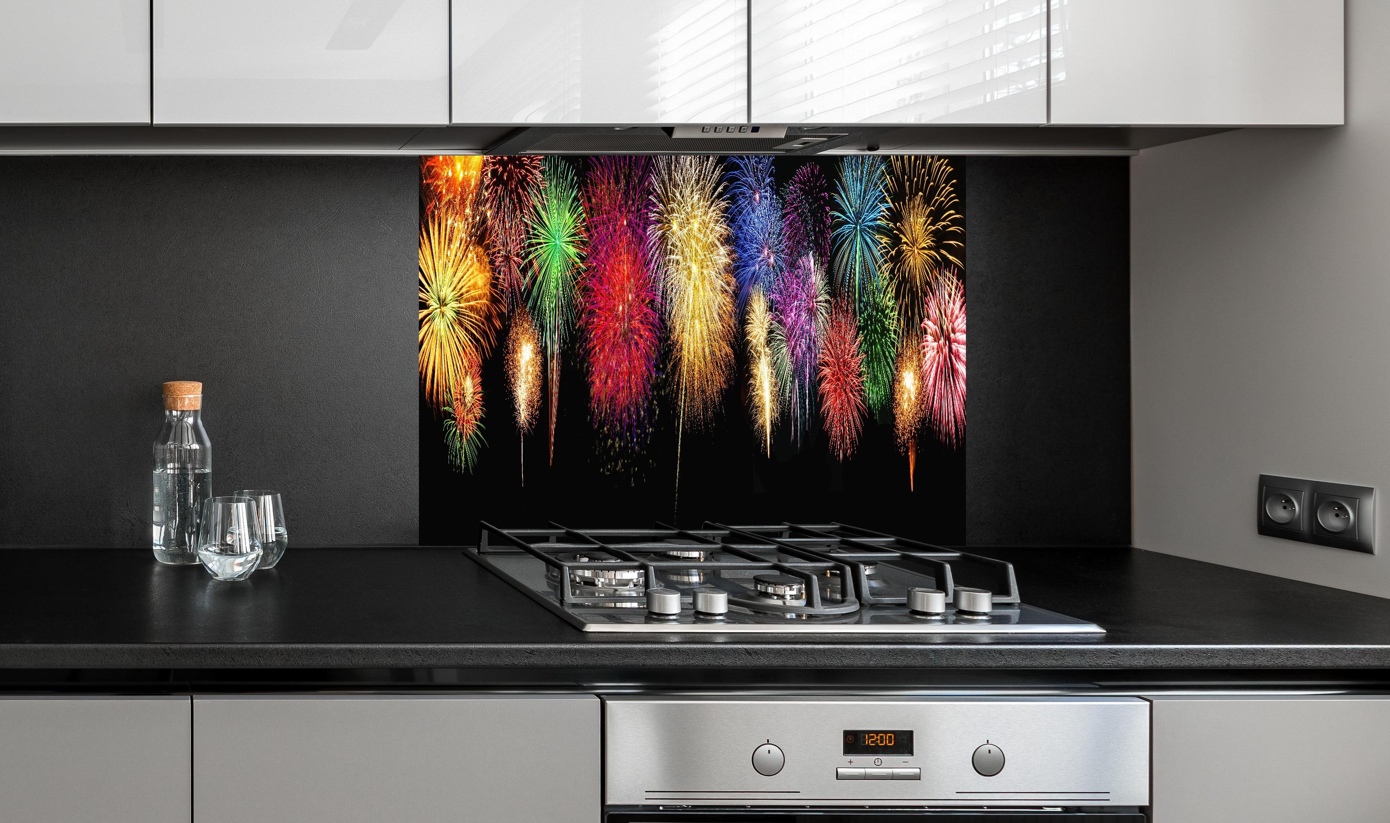 Spritzschutz - Panoramisches Silvesterfeuerwerk in leuchtenden Farben hinter einem Cerankochfeld zwischen Holz-Kochutensilien