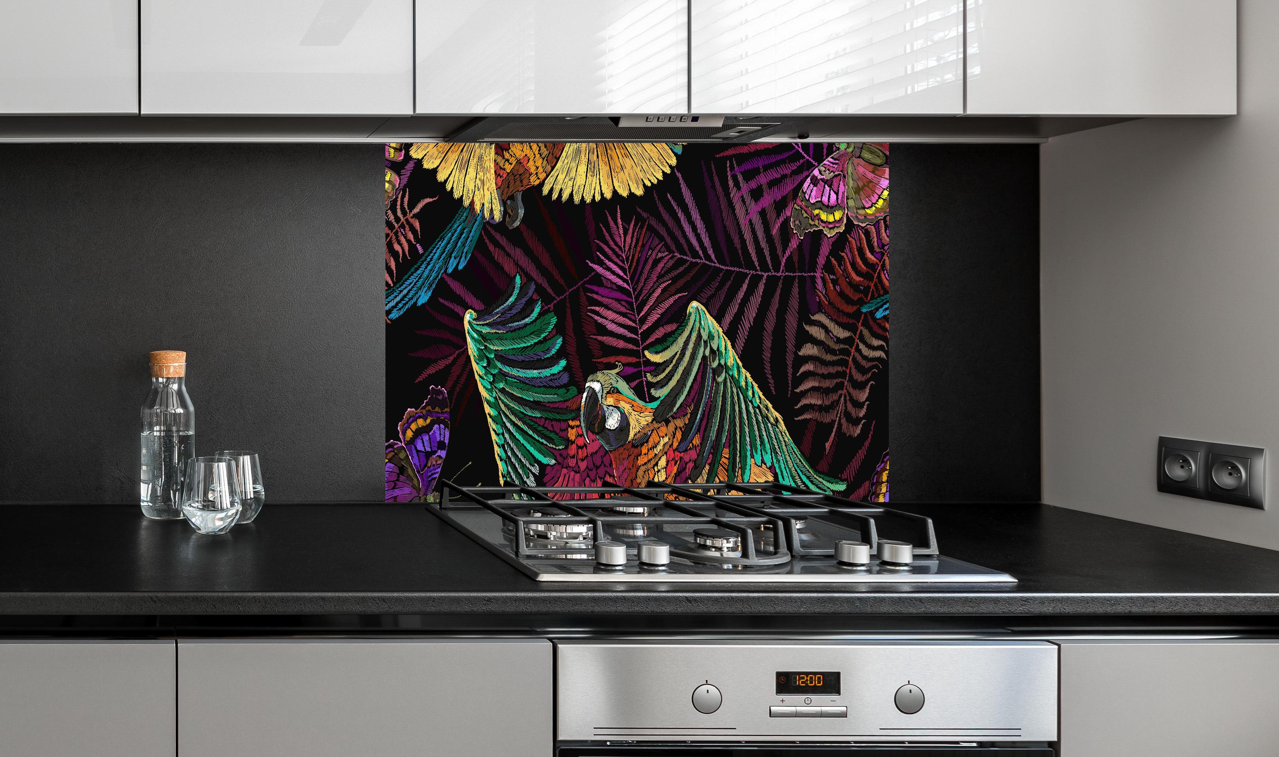 Spritzschutz - Papagaien - Stickmuster hinter einem Cerankochfeld zwischen Holz-Kochutensilien