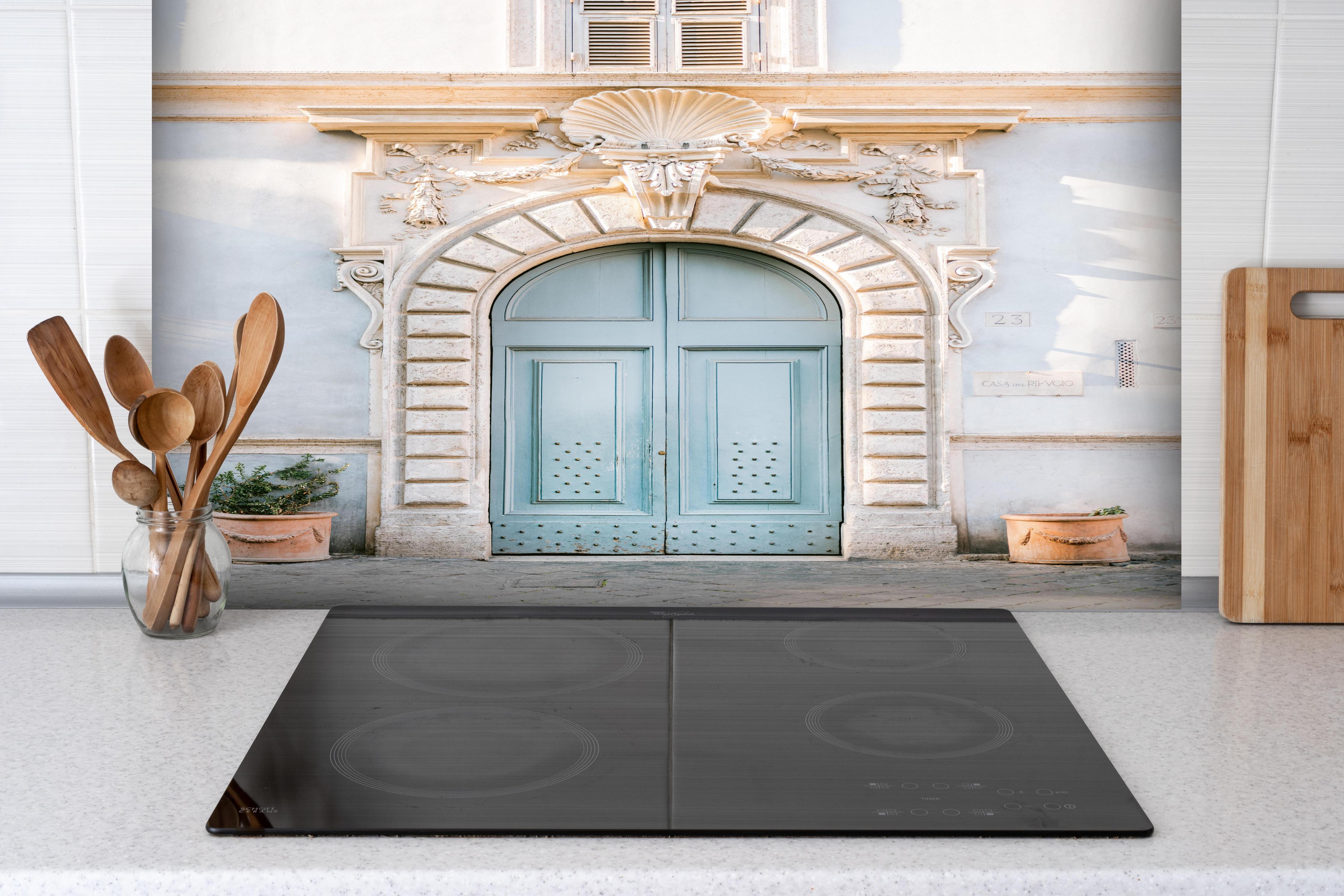 Spritzschutz - Pastellblauer Eingang römische Architektur hinter einem Cerankochfeld zwischen Holz-Kochutensilien