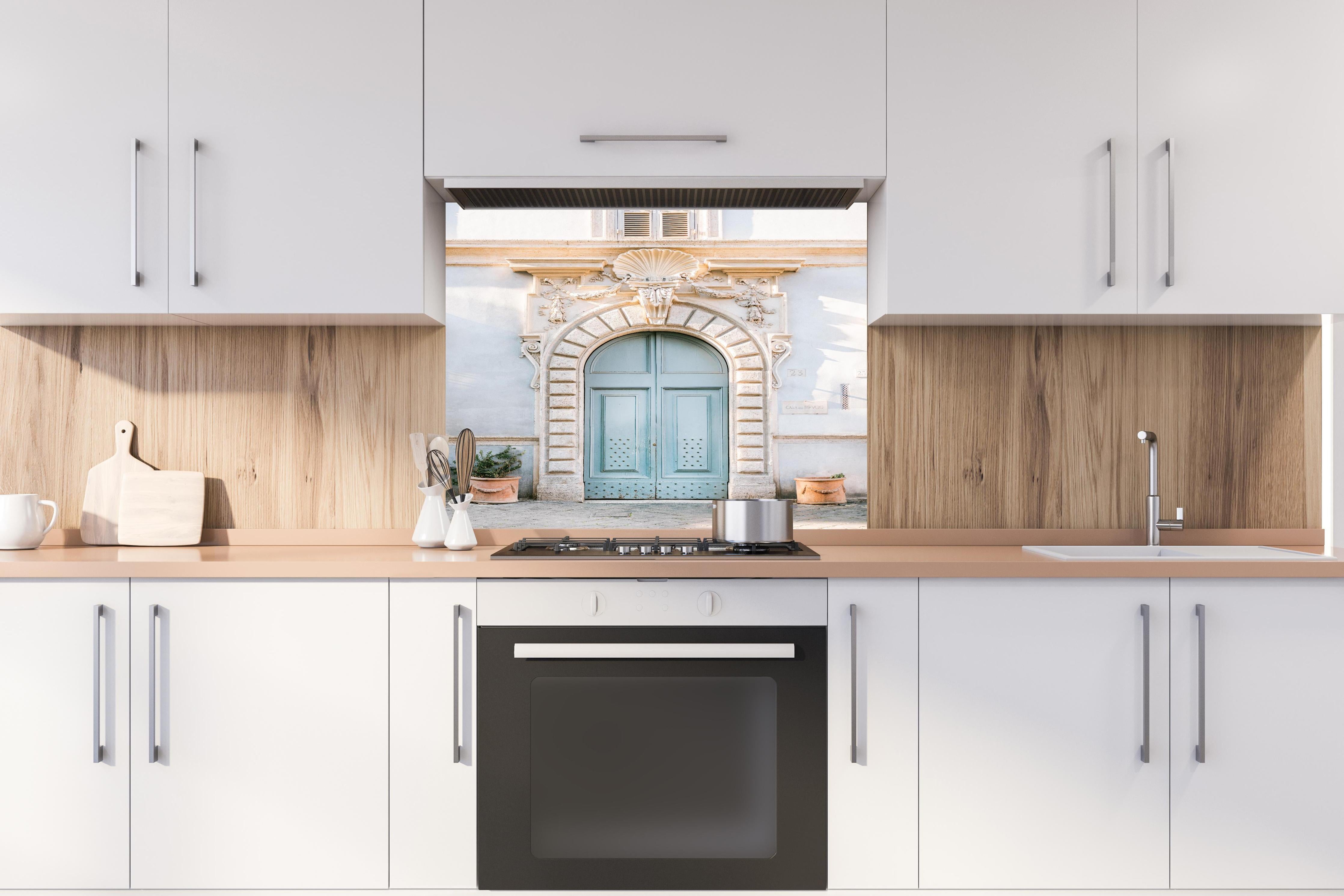 Spritzschutz - Pastellblauer Eingang römische Architektur hinter einem Cerankochfeld zwischen Holz-Kochutensilien