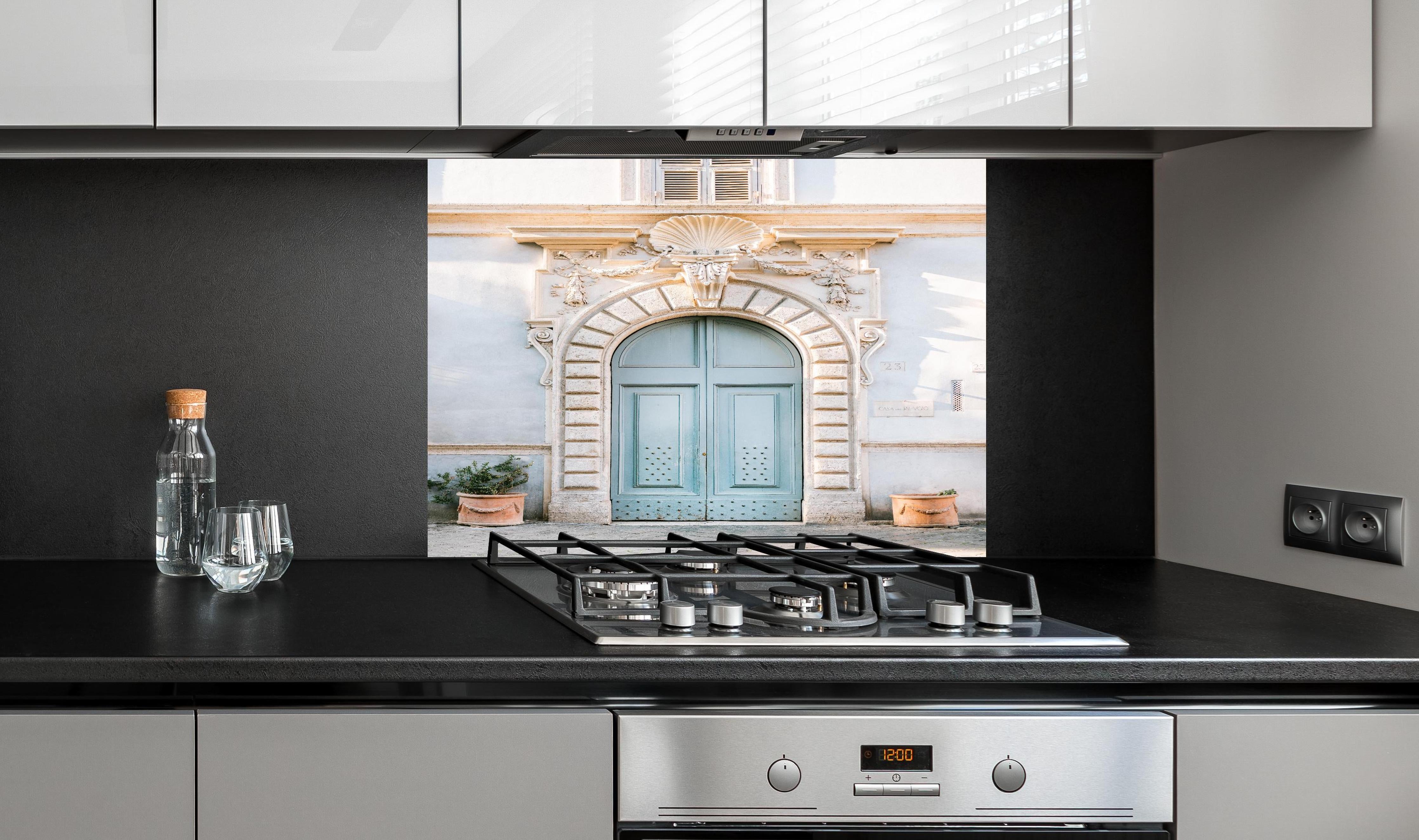 Spritzschutz - Pastellblauer Eingang römische Architektur hinter einem Cerankochfeld zwischen Holz-Kochutensilien