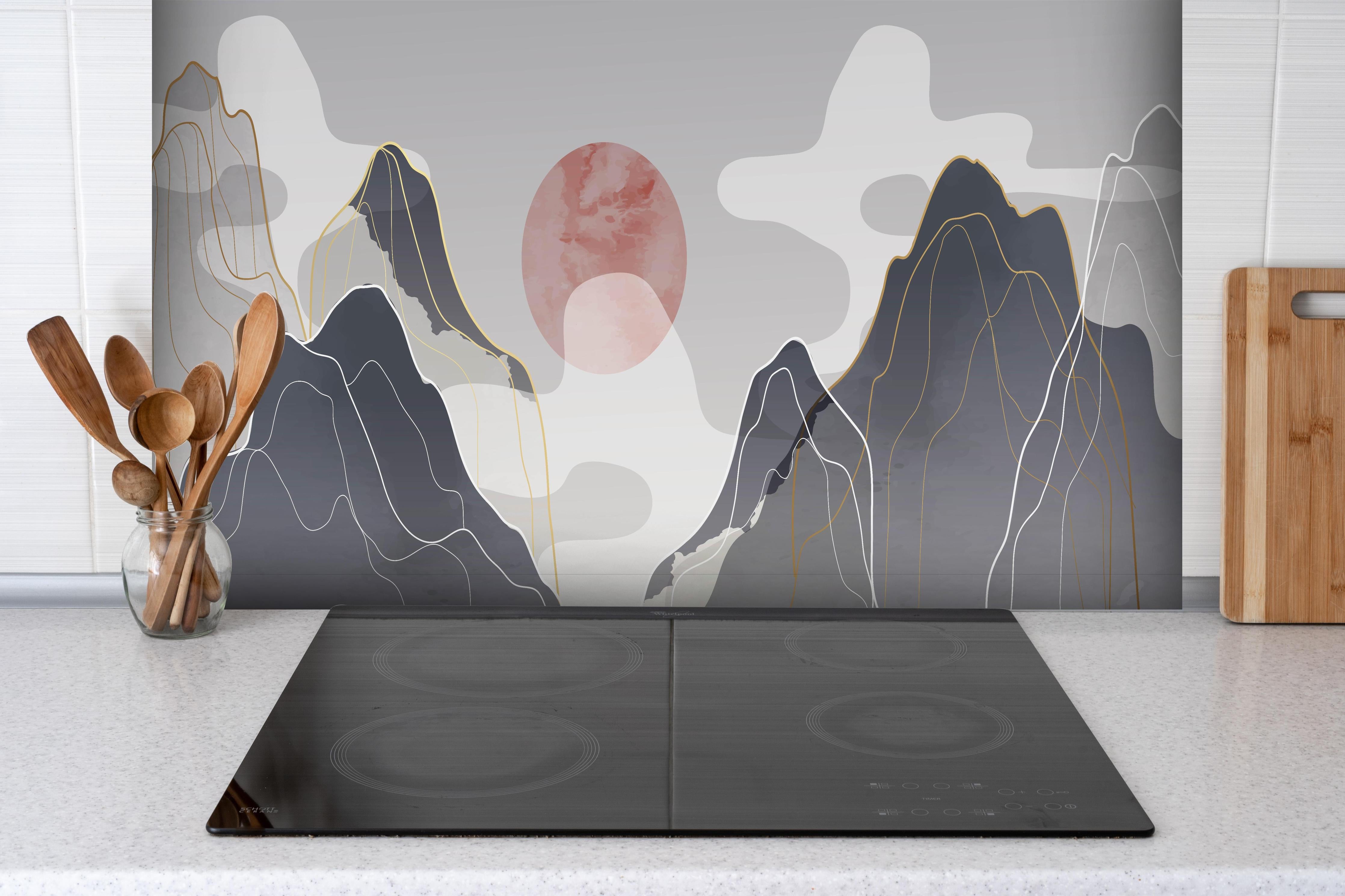 Spritzschutz - Pastellfarbene Berge und Sonnenuntergang hinter einem Cerankochfeld zwischen Holz-Kochutensilien