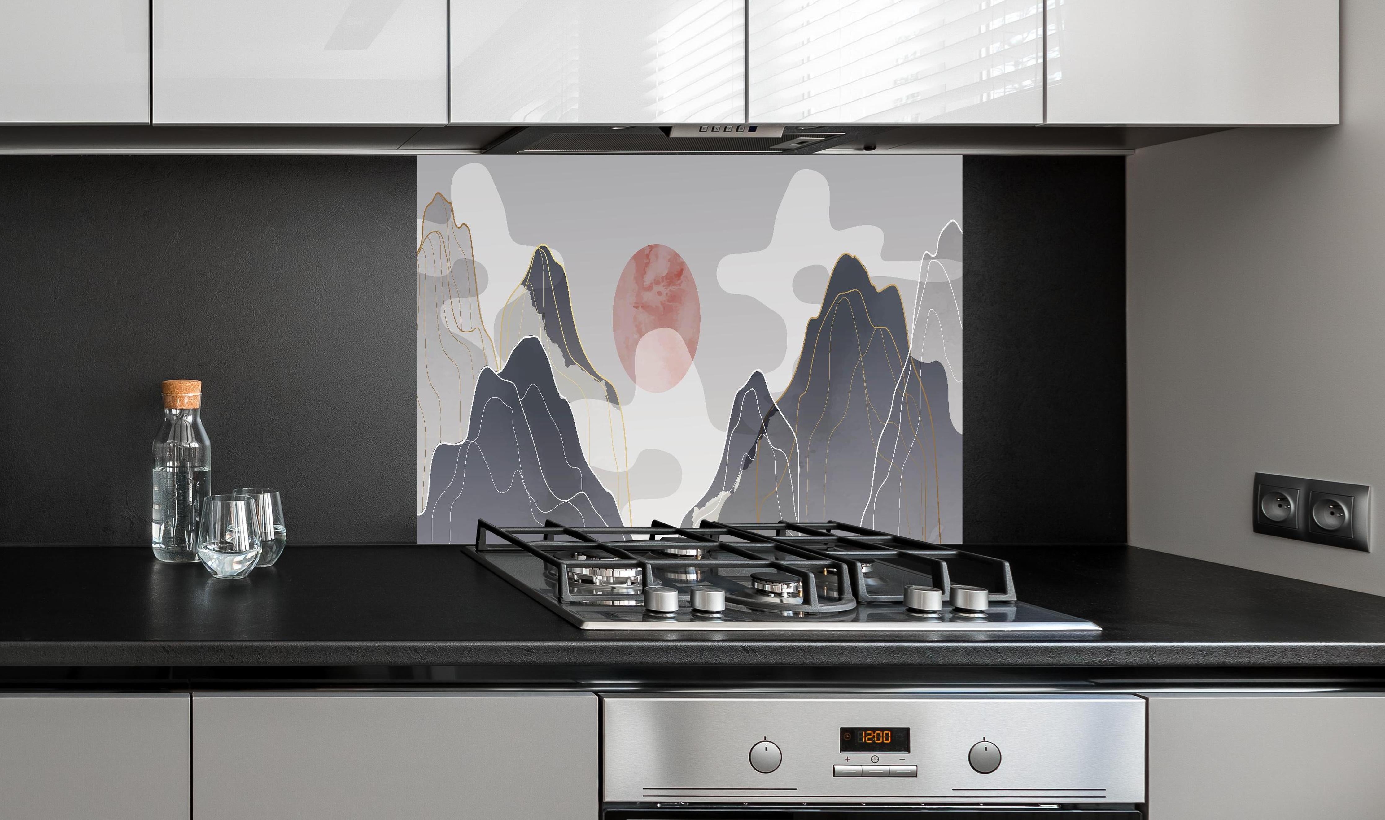 Spritzschutz - Pastellfarbene Berge und Sonnenuntergang hinter einem Cerankochfeld zwischen Holz-Kochutensilien