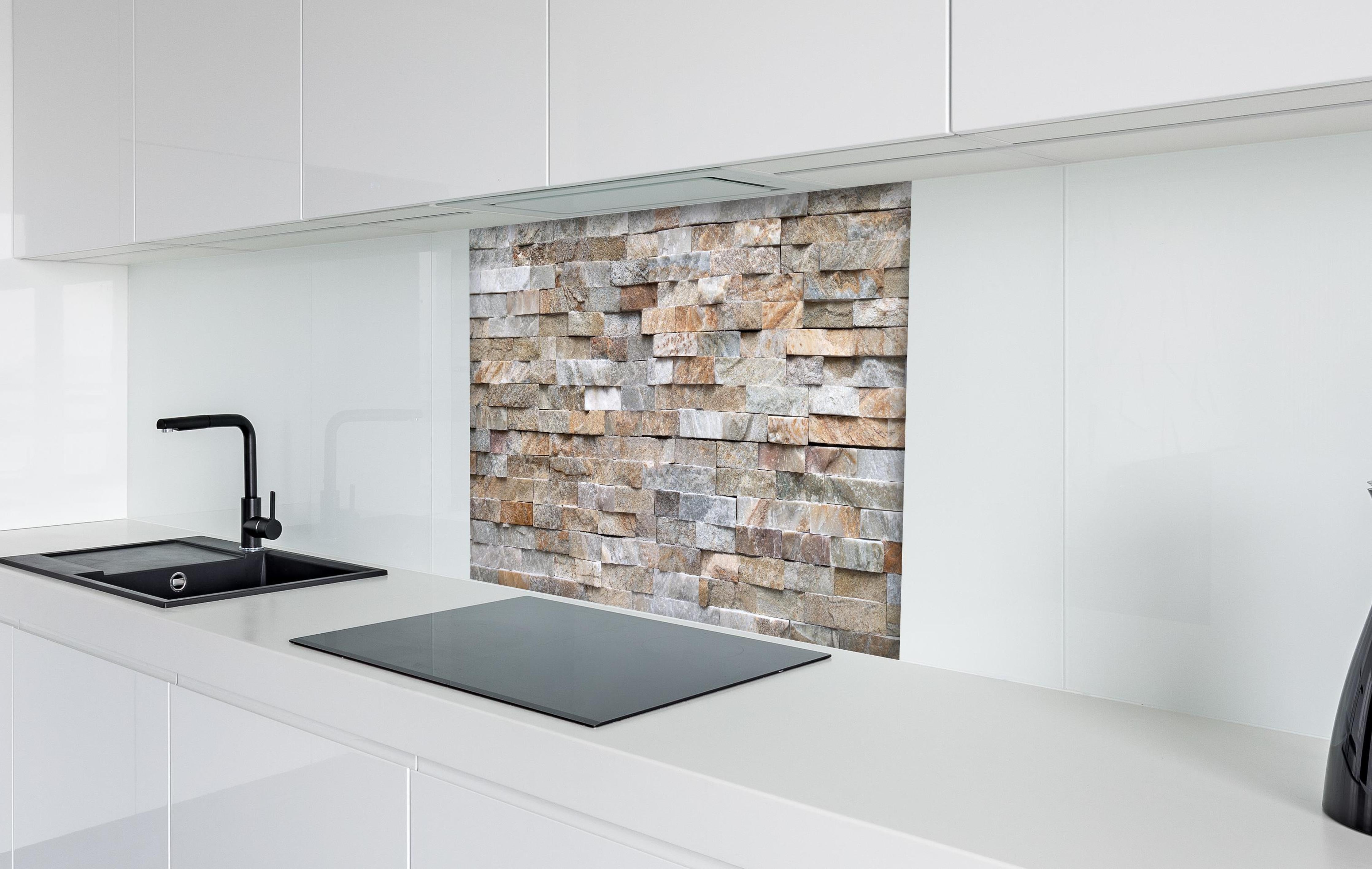 Spritzschutz - Pastellfarbige Steinmauer hinter einem Cerankochfeld zwischen Holz-Kochutensilien