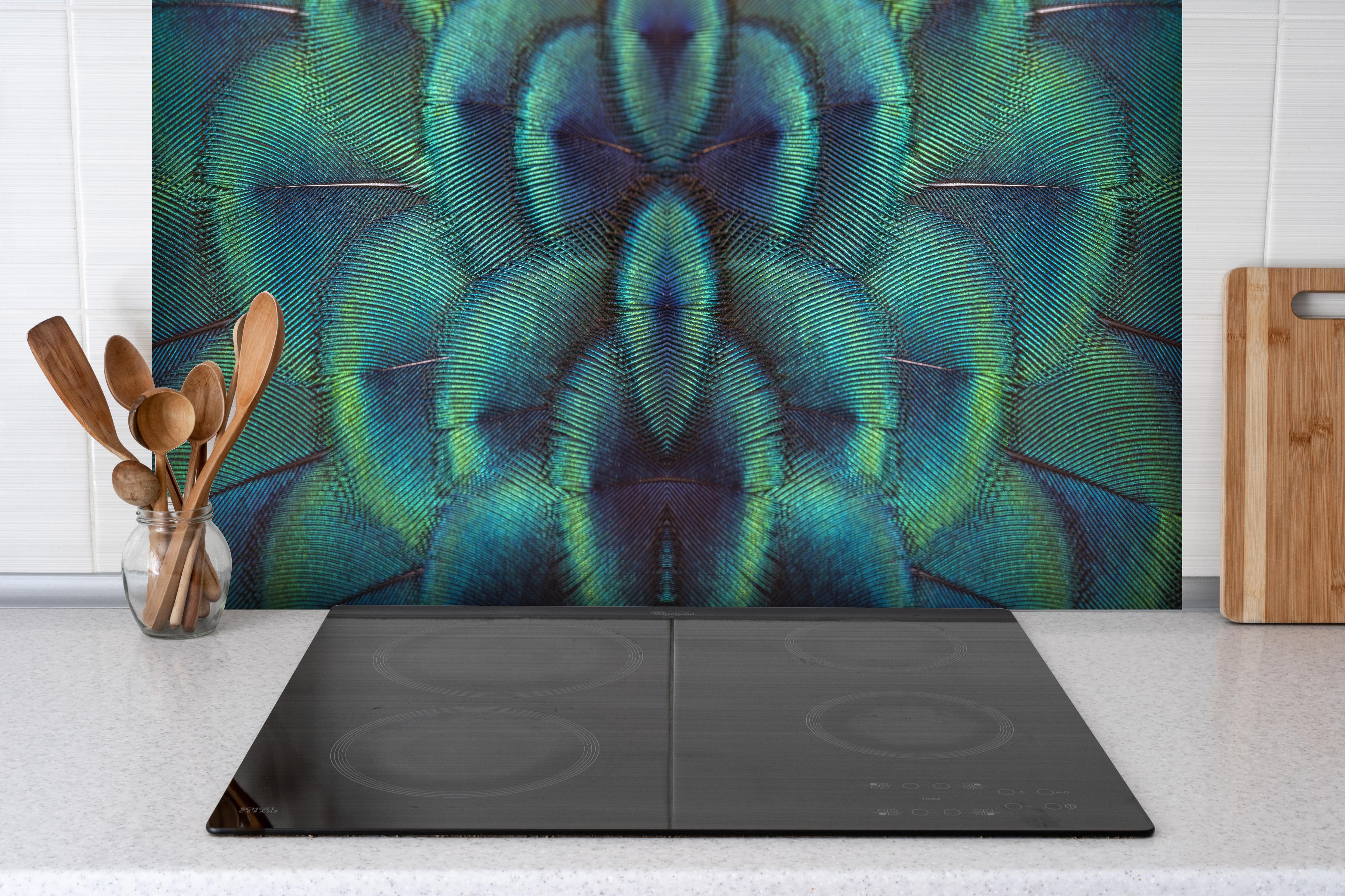 Spritzschutz - Pfauenfedern - Nahaufnahme hinter einem Cerankochfeld zwischen Holz-Kochutensilien