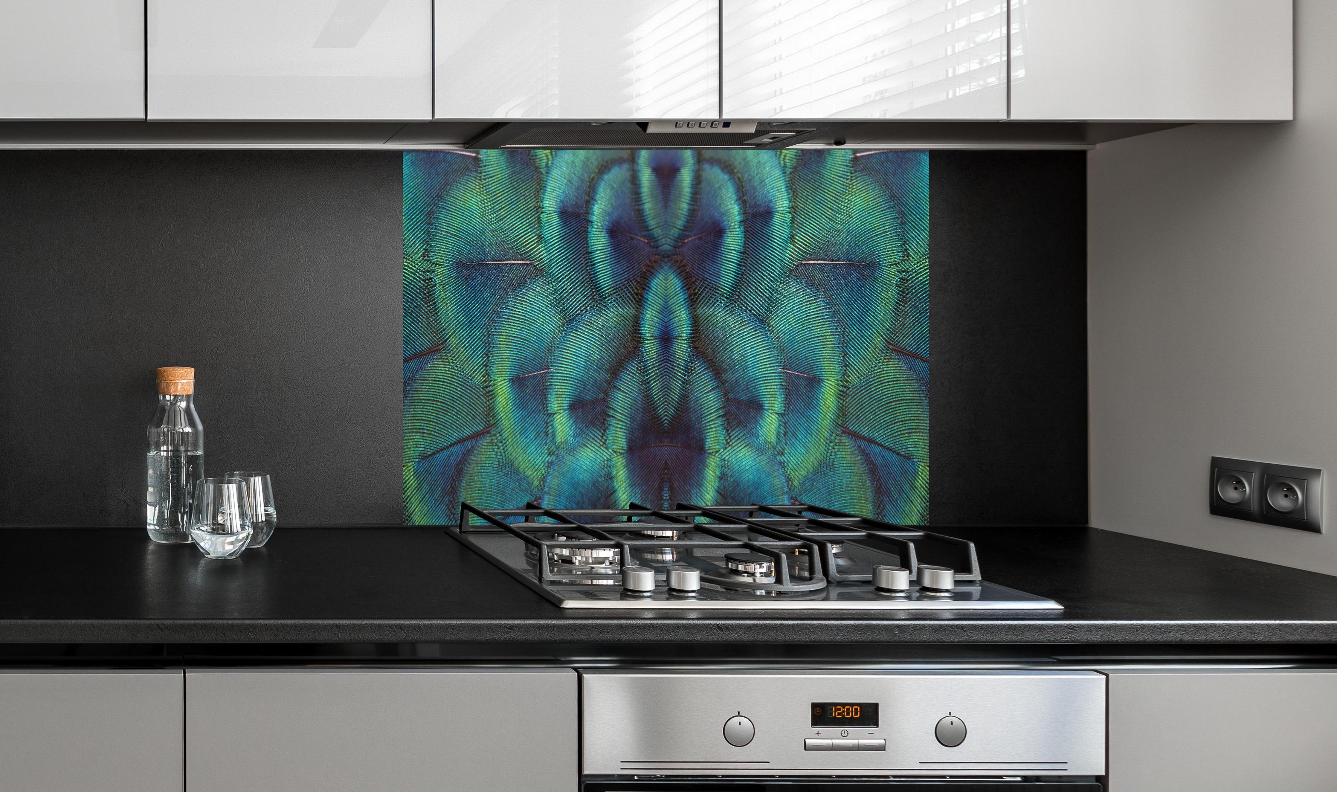 Spritzschutz - Pfauenfedern - Nahaufnahme hinter einem Cerankochfeld zwischen Holz-Kochutensilien