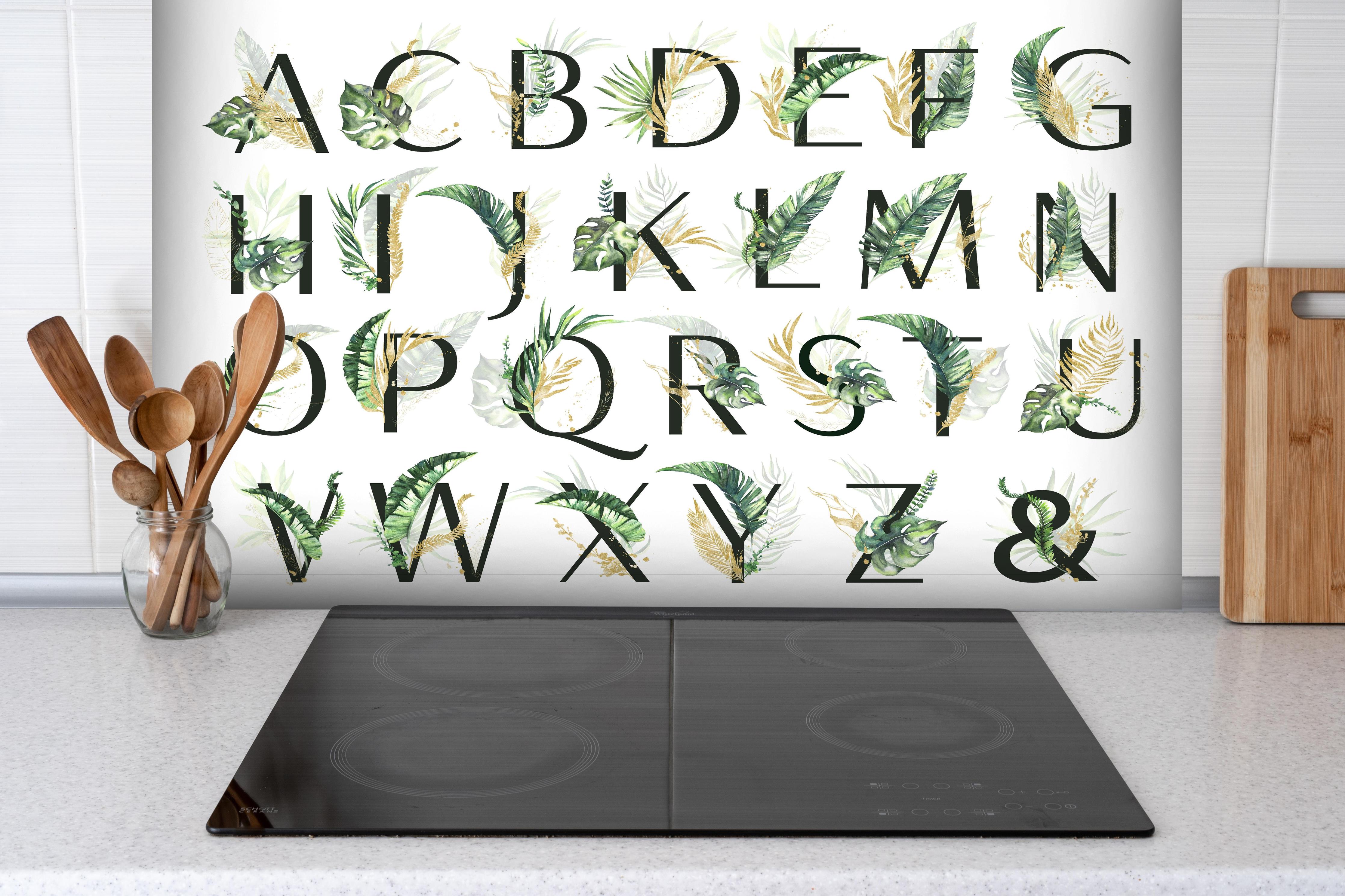 Spritzschutz - Pflanzliche Alphabet Sammlung hinter einem Cerankochfeld zwischen Holz-Kochutensilien