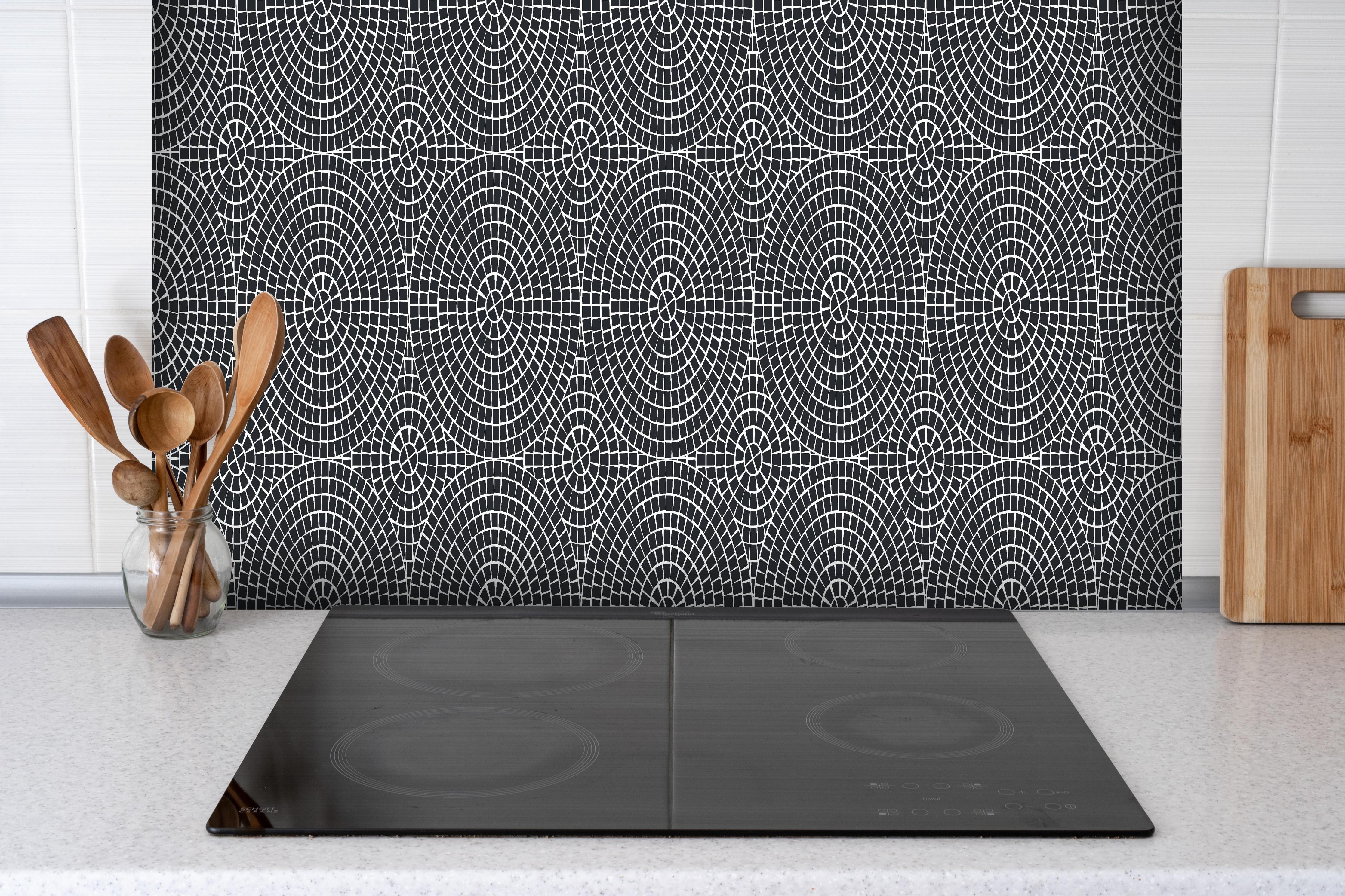 Spritzschutz - Pietre Mosaico Carbone hinter einem Cerankochfeld zwischen Holz-Kochutensilien