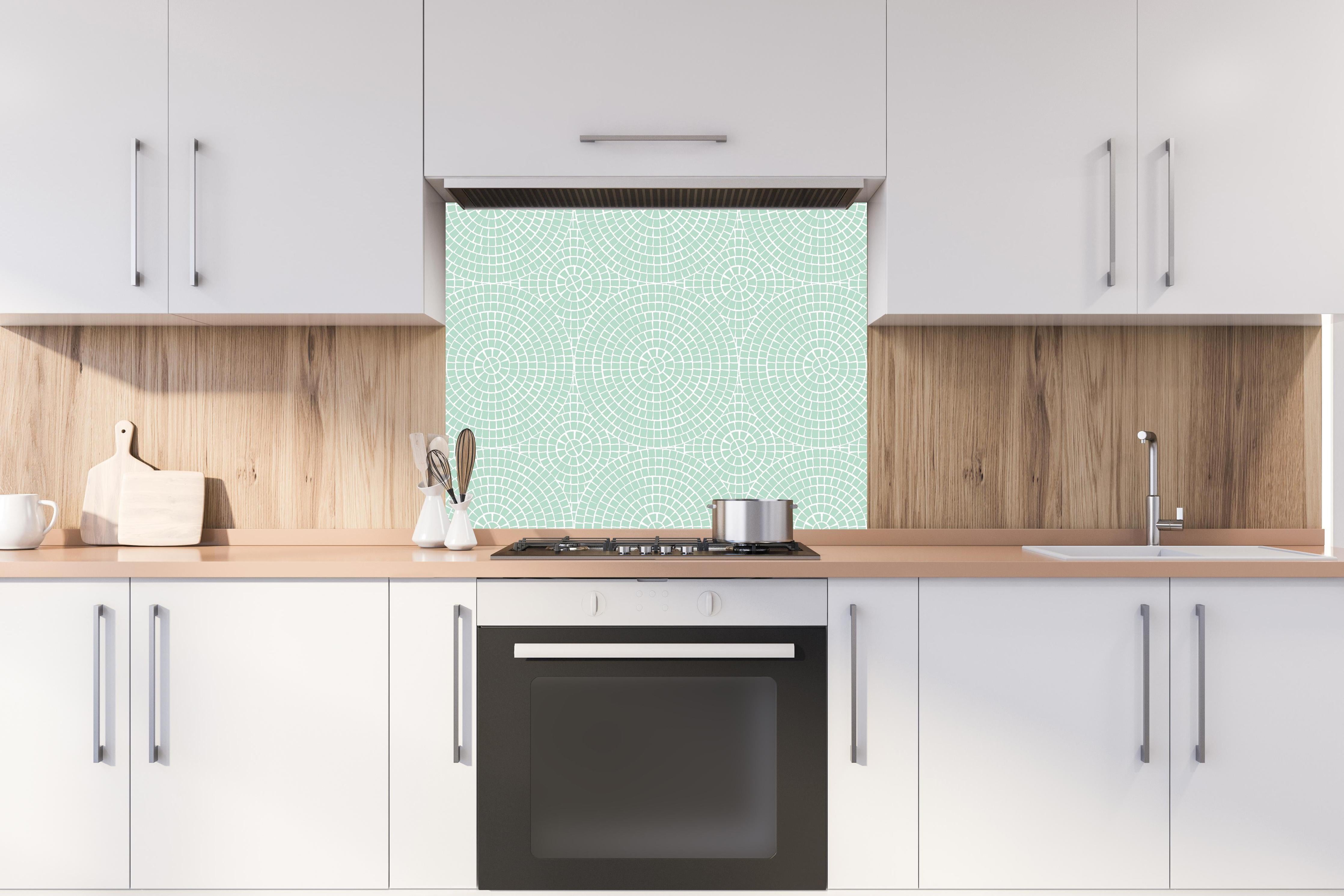 Spritzschutz - Pietre Mosaico Menta hinter einem Cerankochfeld zwischen Holz-Kochutensilien