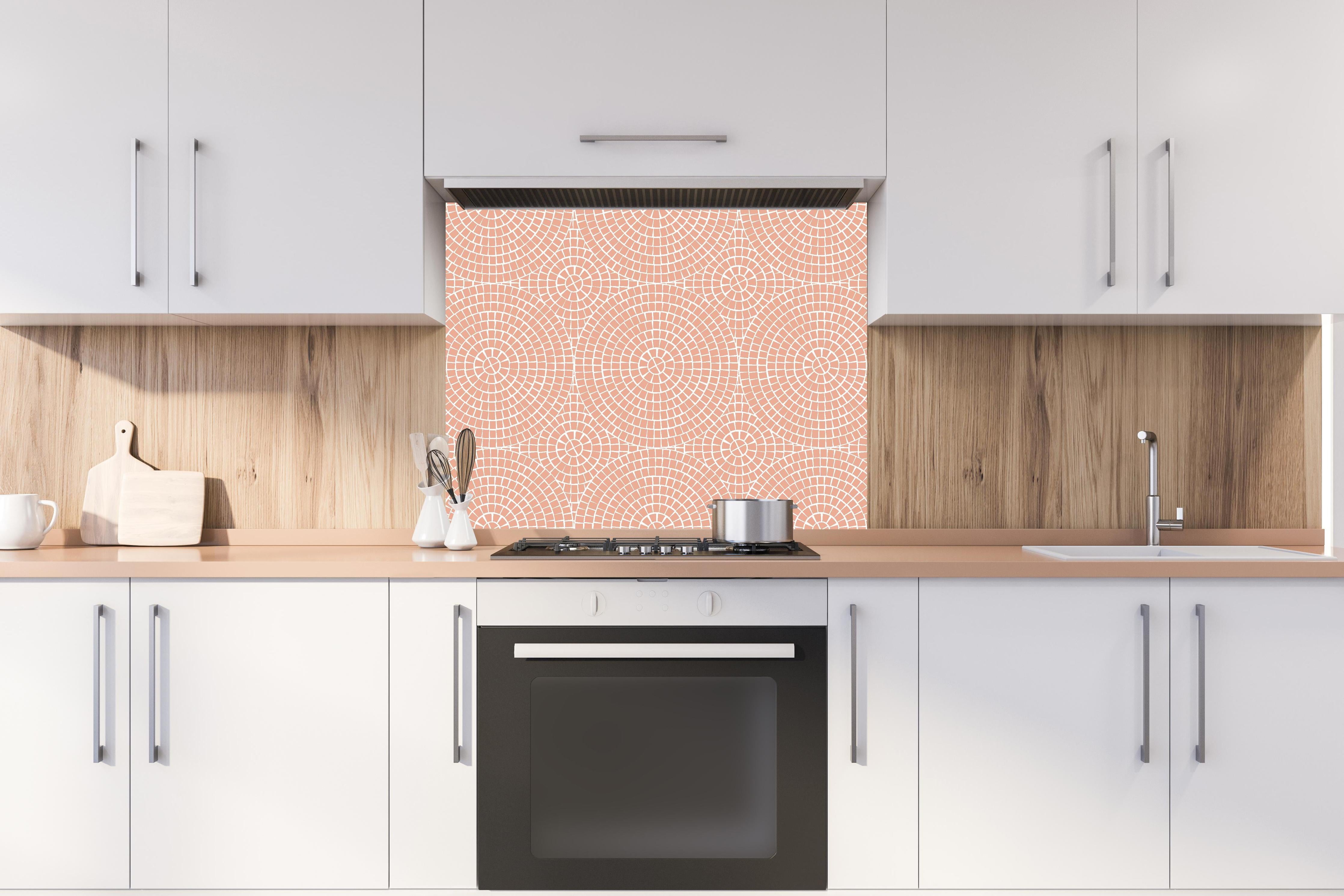 Spritzschutz - Pietre Mosaico Salmone hinter einem Cerankochfeld zwischen Holz-Kochutensilien
