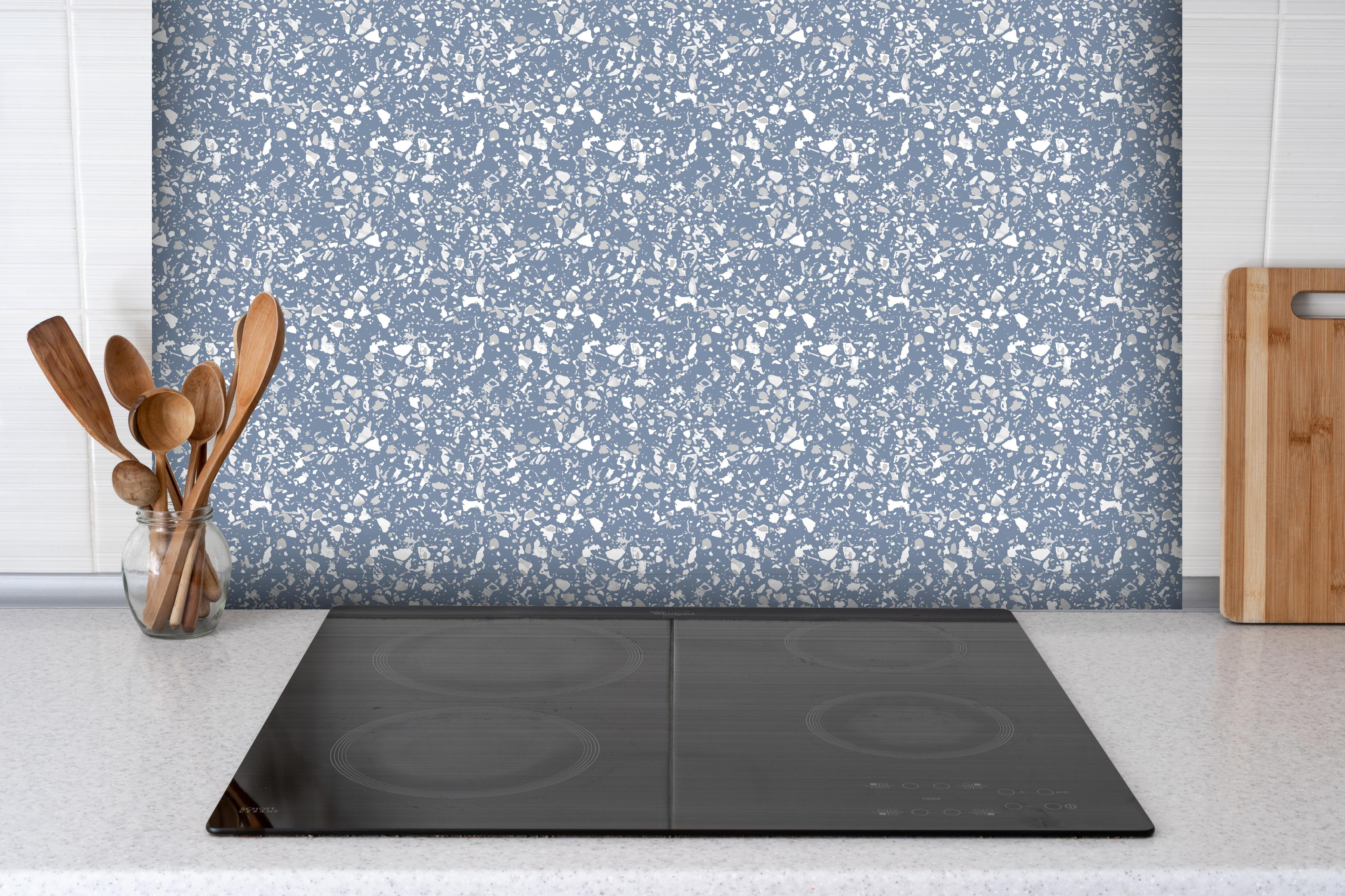 Spritzschutz - Pietre Terrazzo Azzurro polvere hinter einem Cerankochfeld zwischen Holz-Kochutensilien