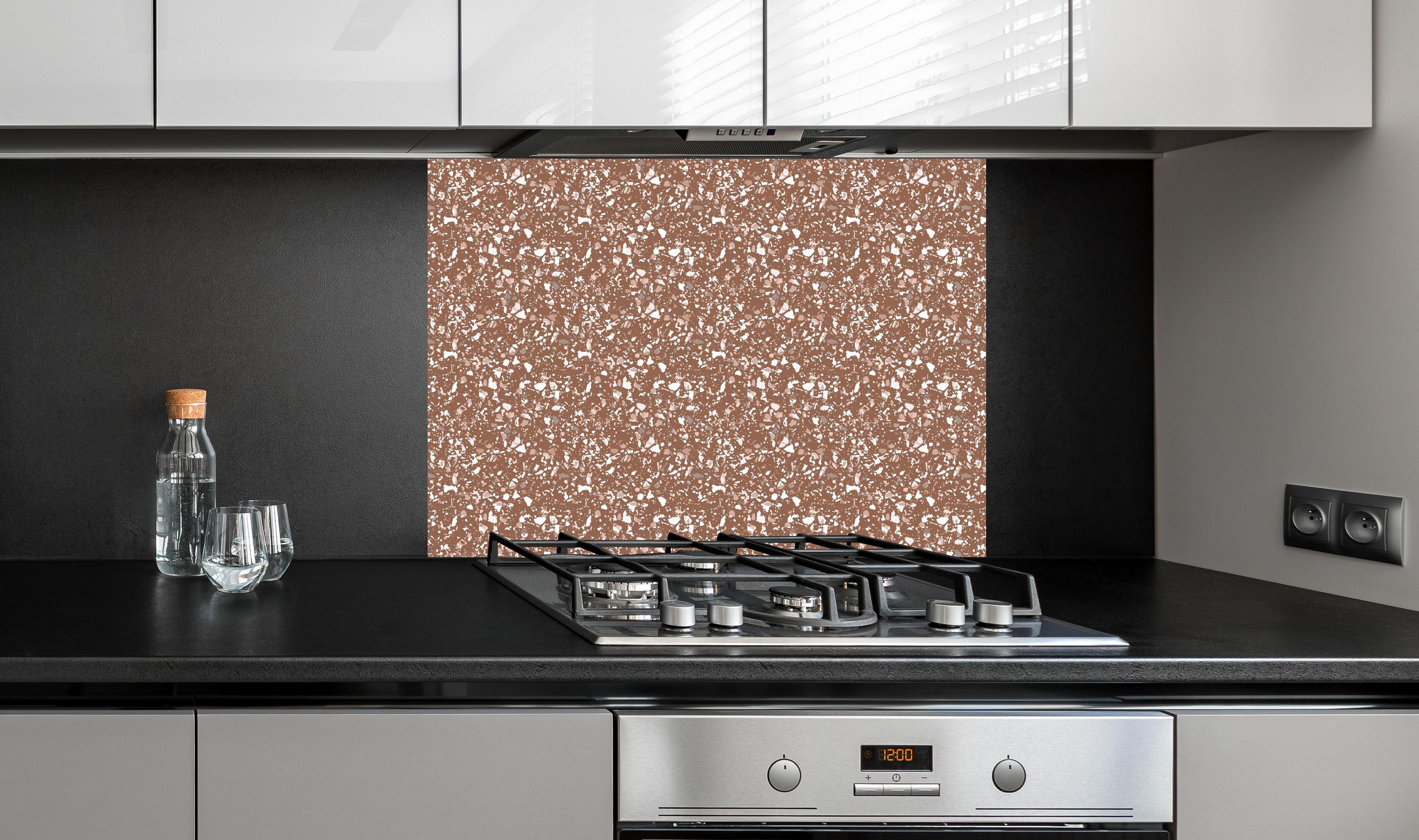 Spritzschutz - Pietre Terrazzo Cannella hinter einem Cerankochfeld zwischen Holz-Kochutensilien