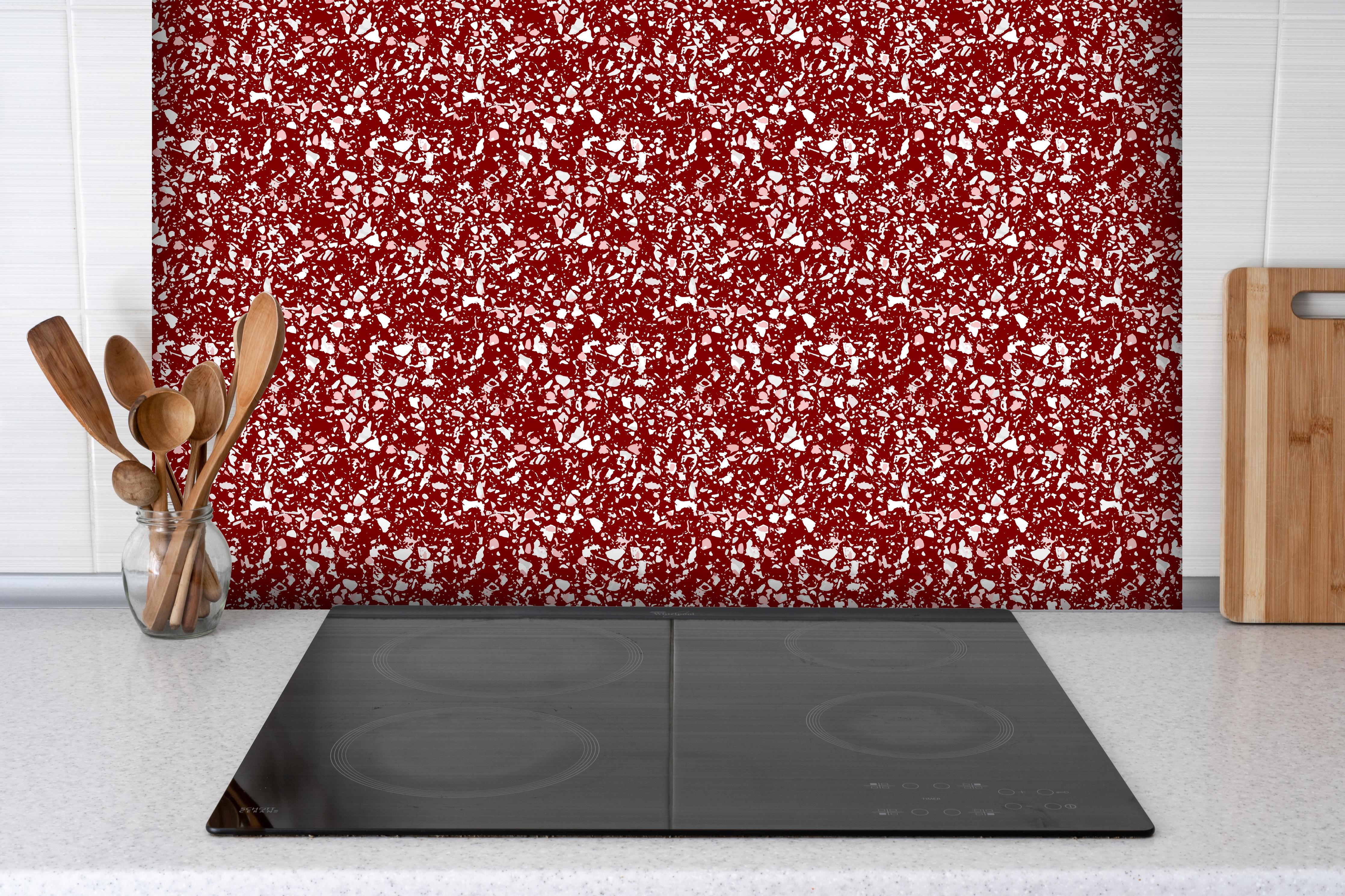 Spritzschutz - Pietre Terrazzo Granata hinter einem Cerankochfeld zwischen Holz-Kochutensilien