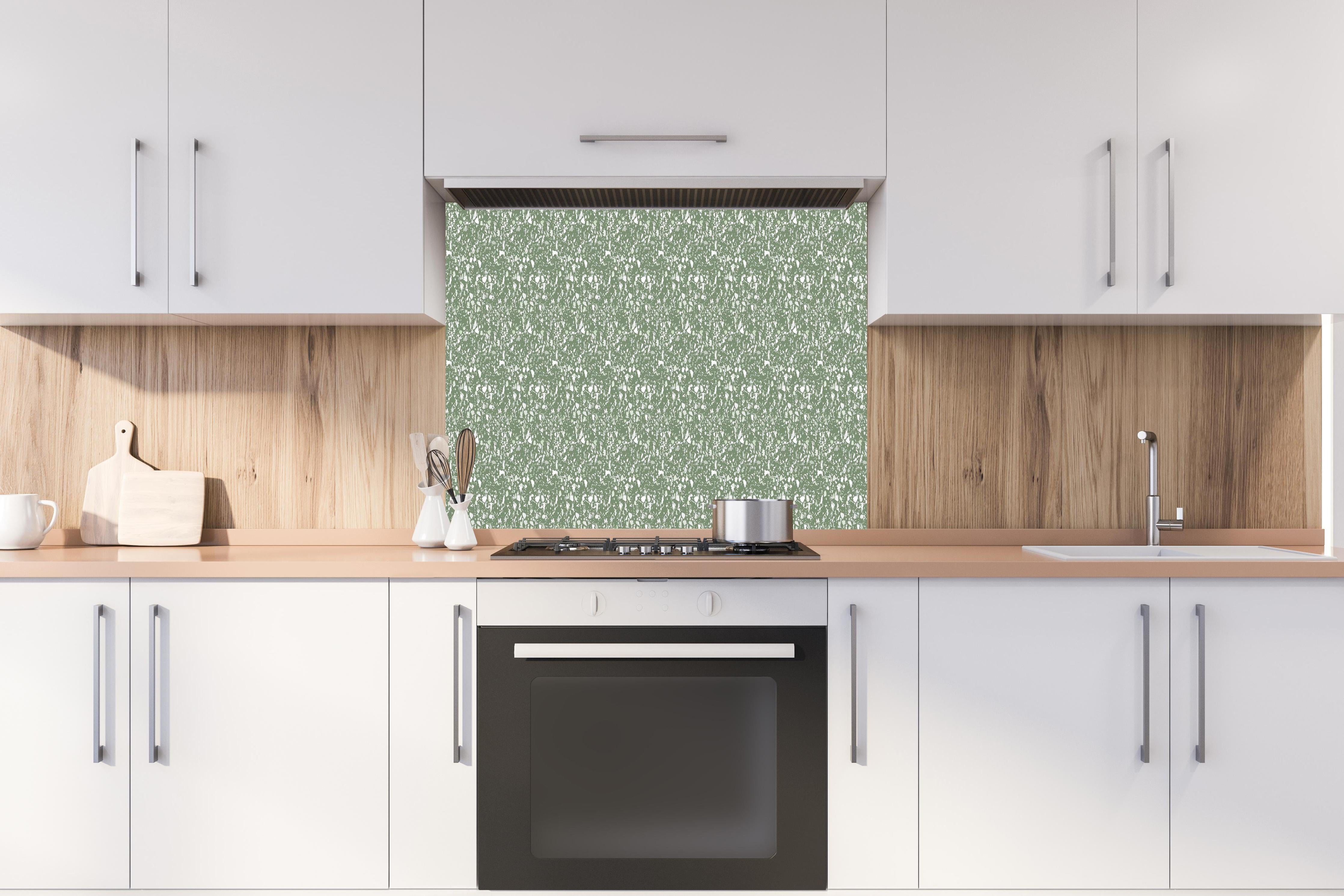 Spritzschutz - Pietre Terrazzo Oliva hinter einem Cerankochfeld zwischen Holz-Kochutensilien