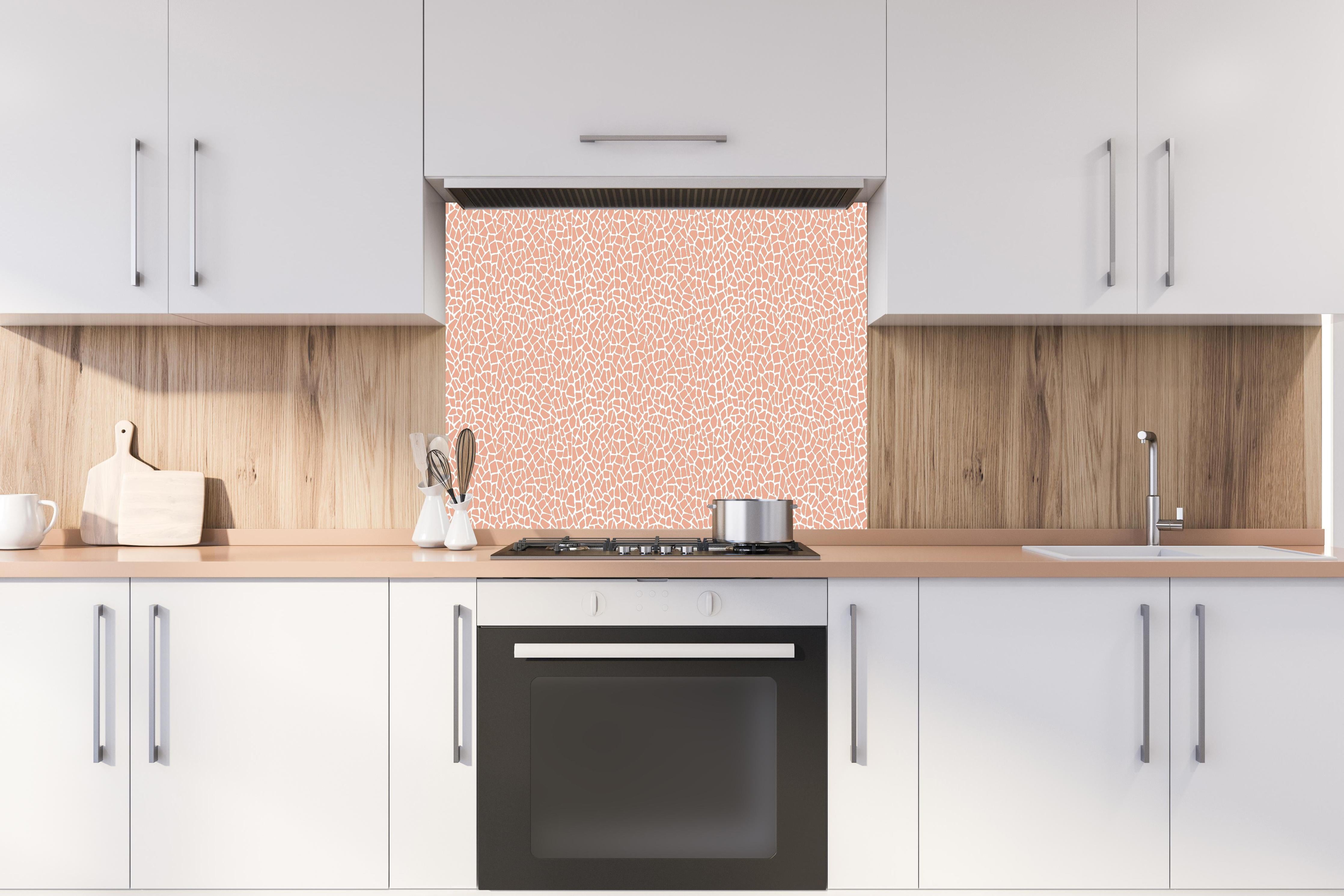 Spritzschutz - Pietre Tessere Salmone hinter einem Cerankochfeld zwischen Holz-Kochutensilien