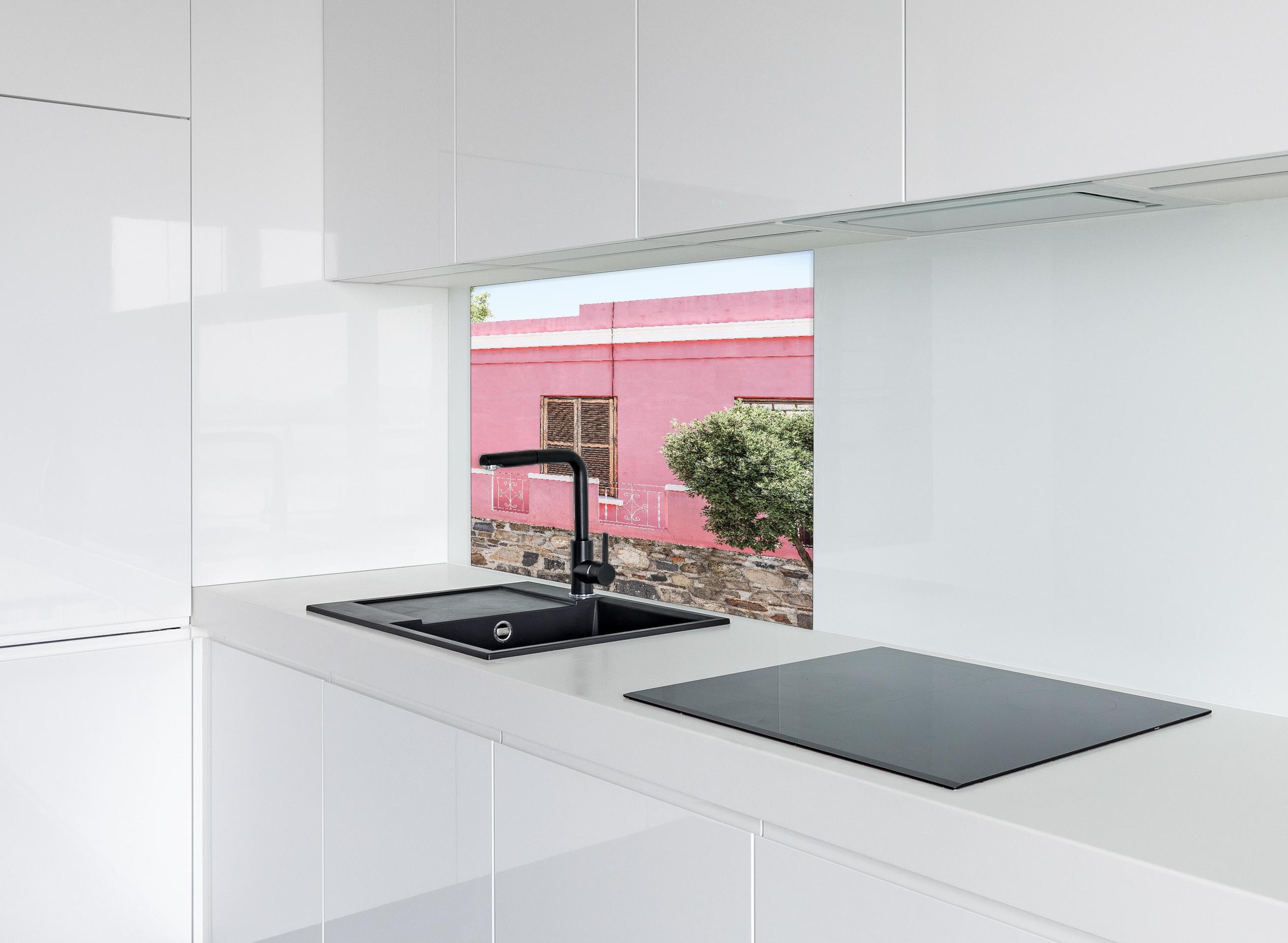 Spritzschutz - Pinkes Haus mit Baum und Steinwand hinter einem Cerankochfeld zwischen Holz-Kochutensilien