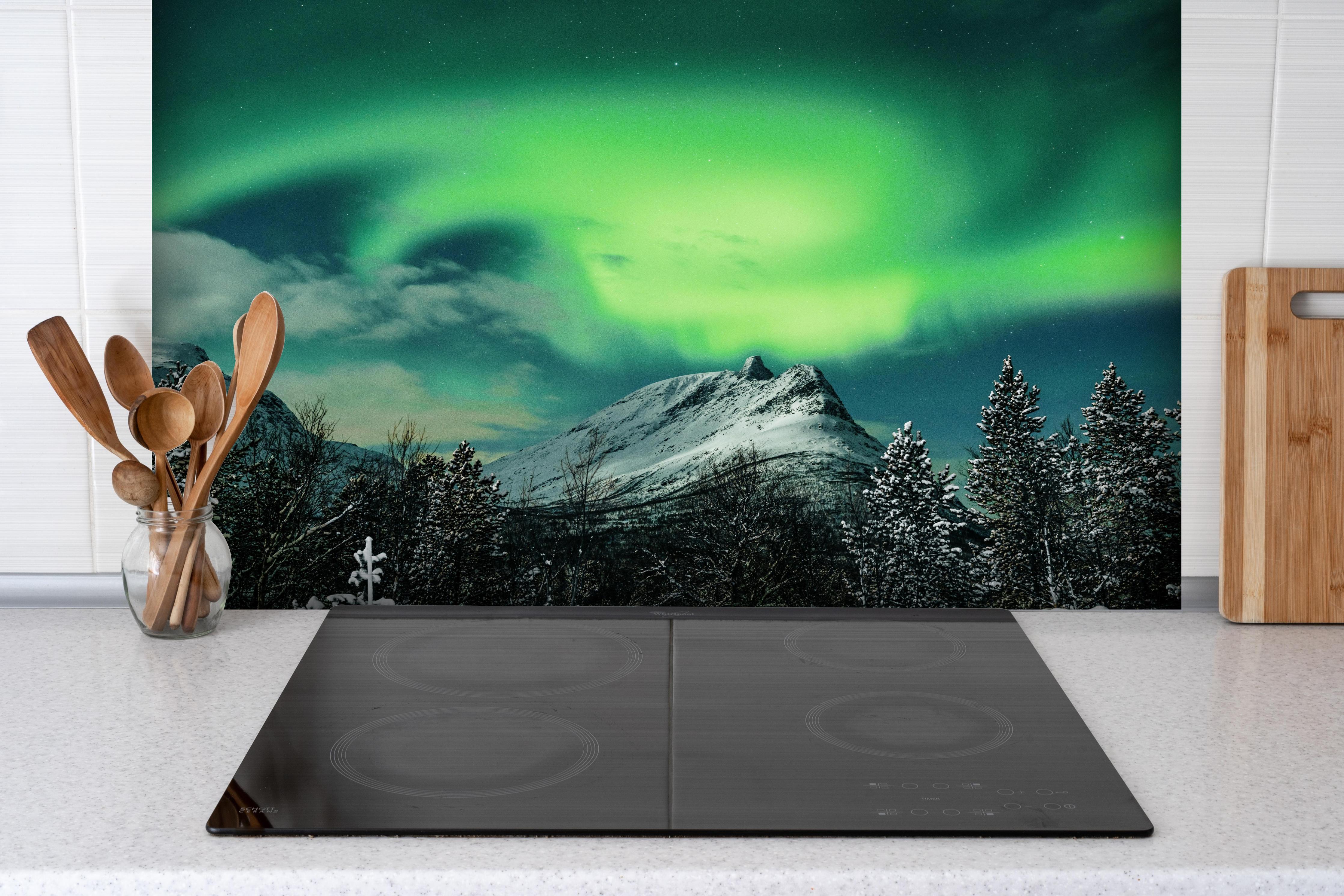 Spritzschutz - Polarlichter über Berg in Nordnorwegen hinter einem Cerankochfeld zwischen Holz-Kochutensilien