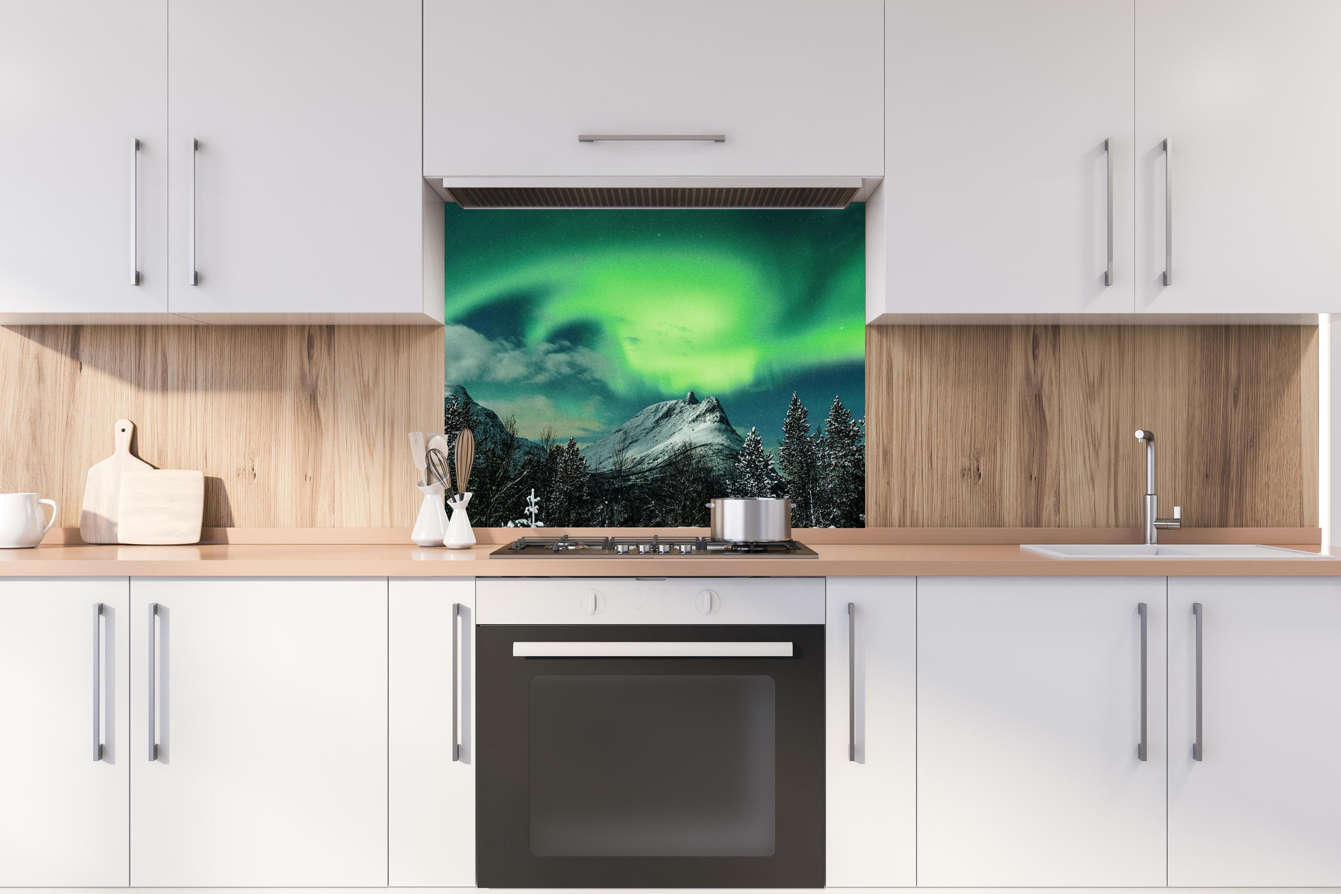 Spritzschutz - Polarlichter über Berg in Nordnorwegen hinter einem Cerankochfeld zwischen Holz-Kochutensilien