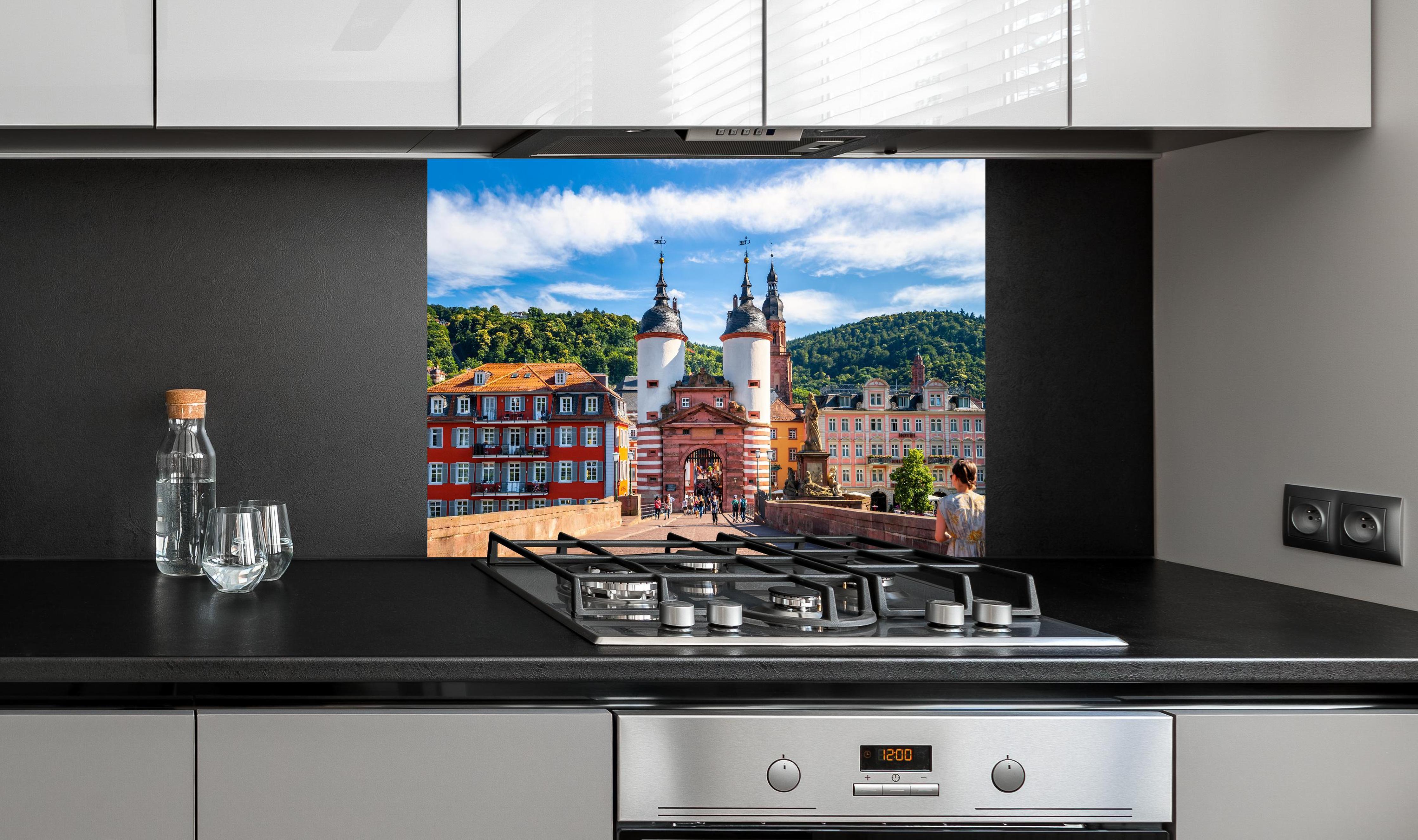 Spritzschutz - Prächtiger Anblick auf Brücke in Heidelberg hinter einem Cerankochfeld zwischen Holz-Kochutensilien