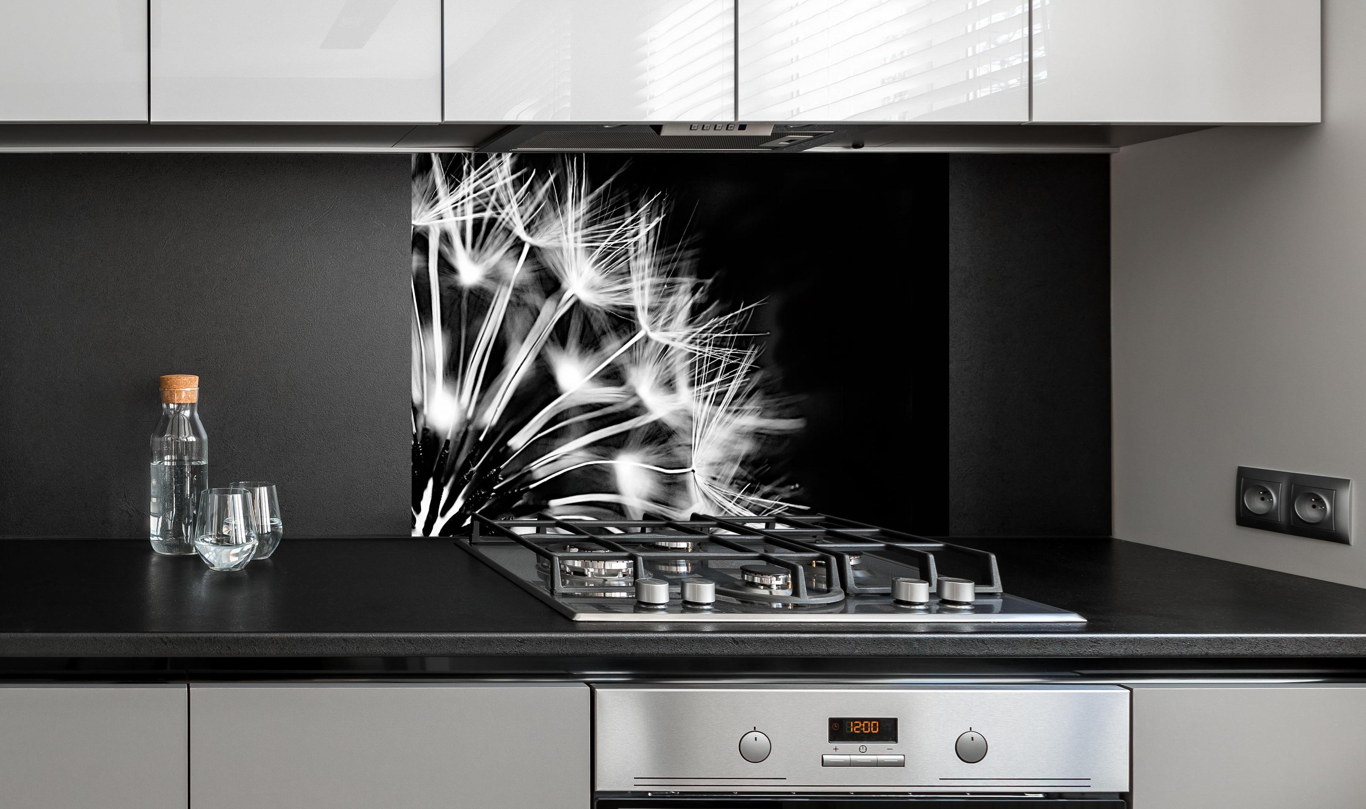 Spritzschutz - Pusteblumen schwarz-weiß Hintergrund hinter einem Cerankochfeld zwischen Holz-Kochutensilien