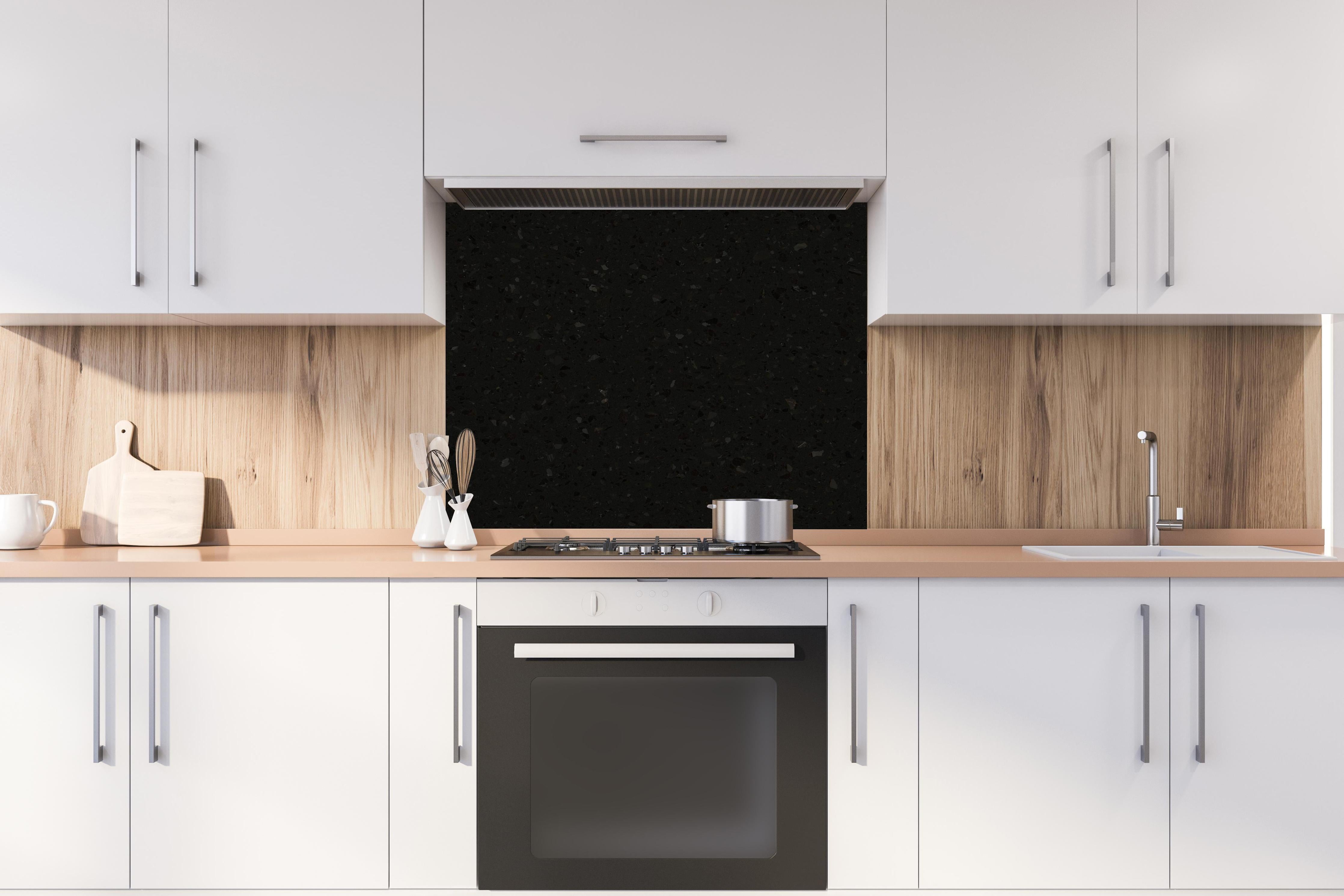 Spritzschutz - Quarz Diamond Charcoal hinter einem Cerankochfeld zwischen Holz-Kochutensilien