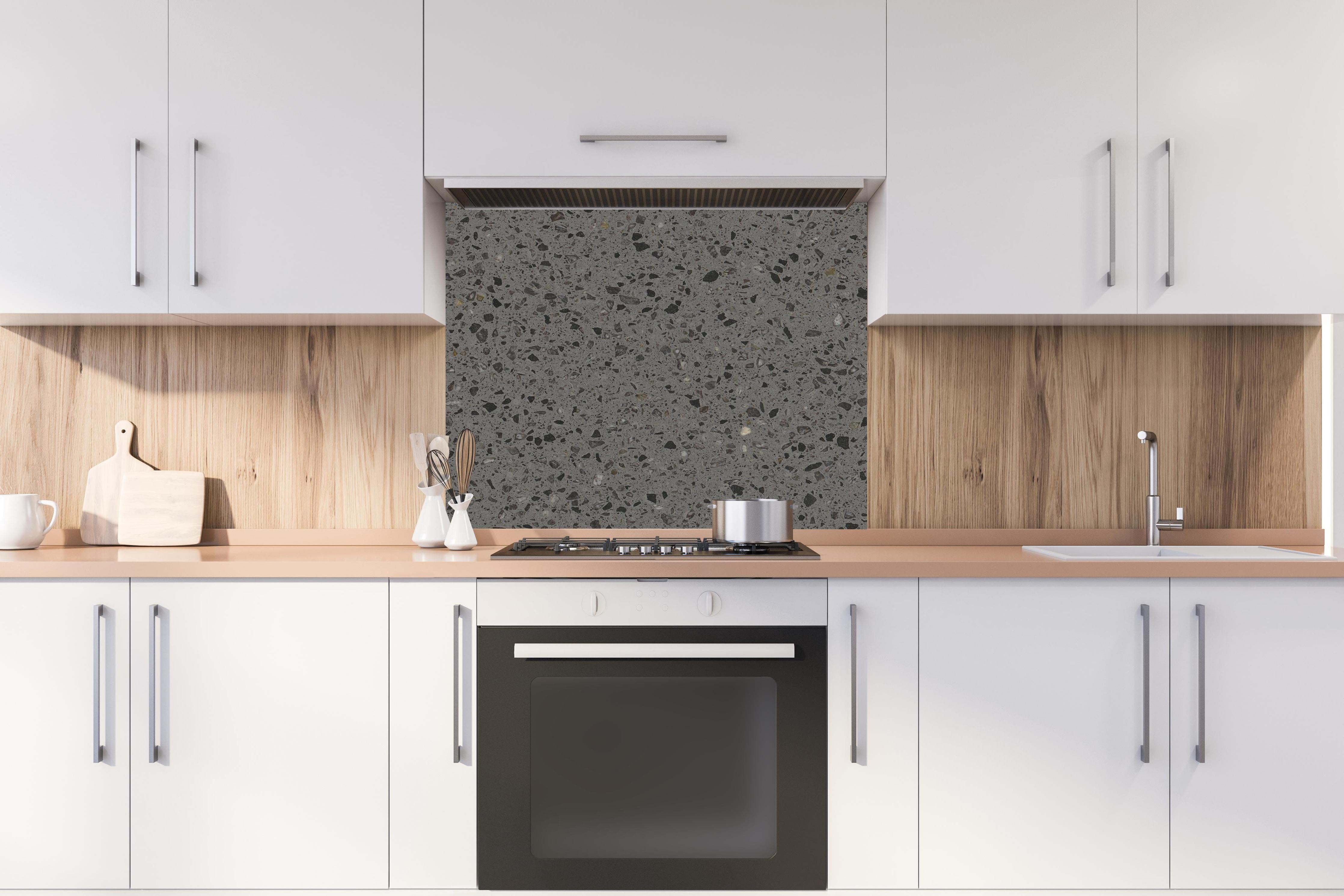 Spritzschutz - Quarz FusionStone Grey hinter einem Cerankochfeld zwischen Holz-Kochutensilien