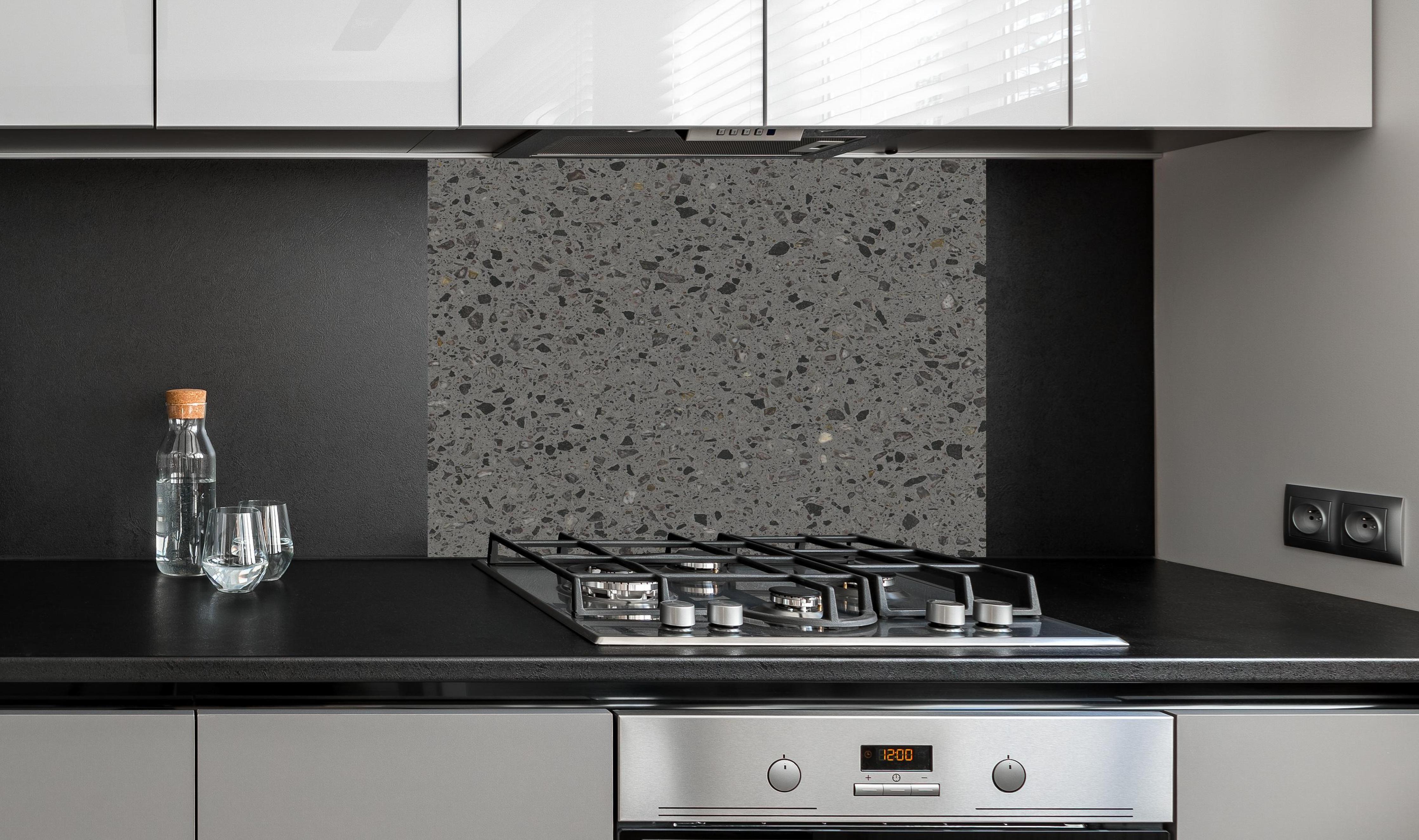 Spritzschutz - Quarz FusionStone Grey hinter einem Cerankochfeld zwischen Holz-Kochutensilien