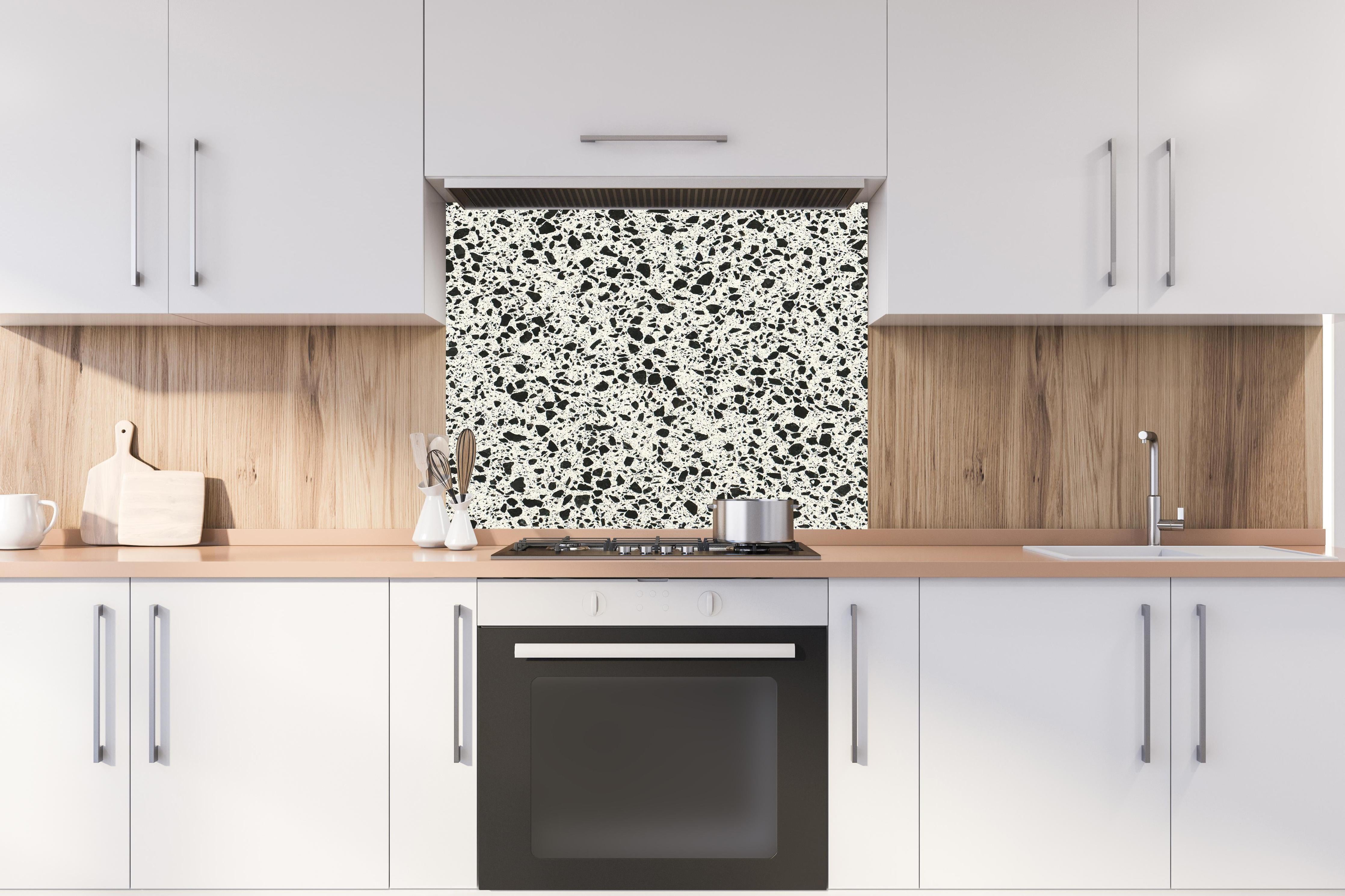 Spritzschutz - Quarz FusionStone White hinter einem Cerankochfeld zwischen Holz-Kochutensilien