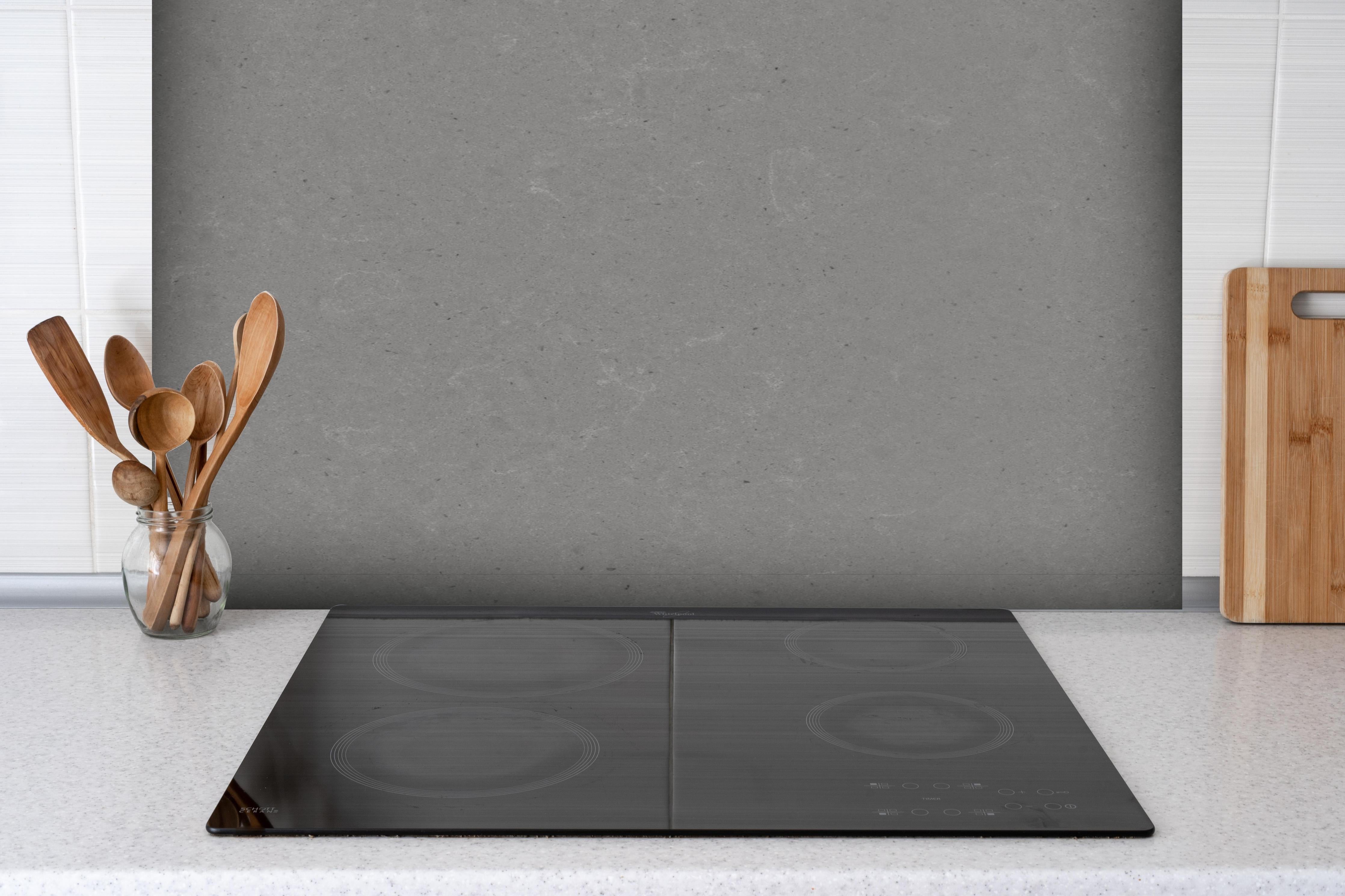 Spritzschutz - Quarz Marble Grey hinter einem Cerankochfeld zwischen Holz-Kochutensilien