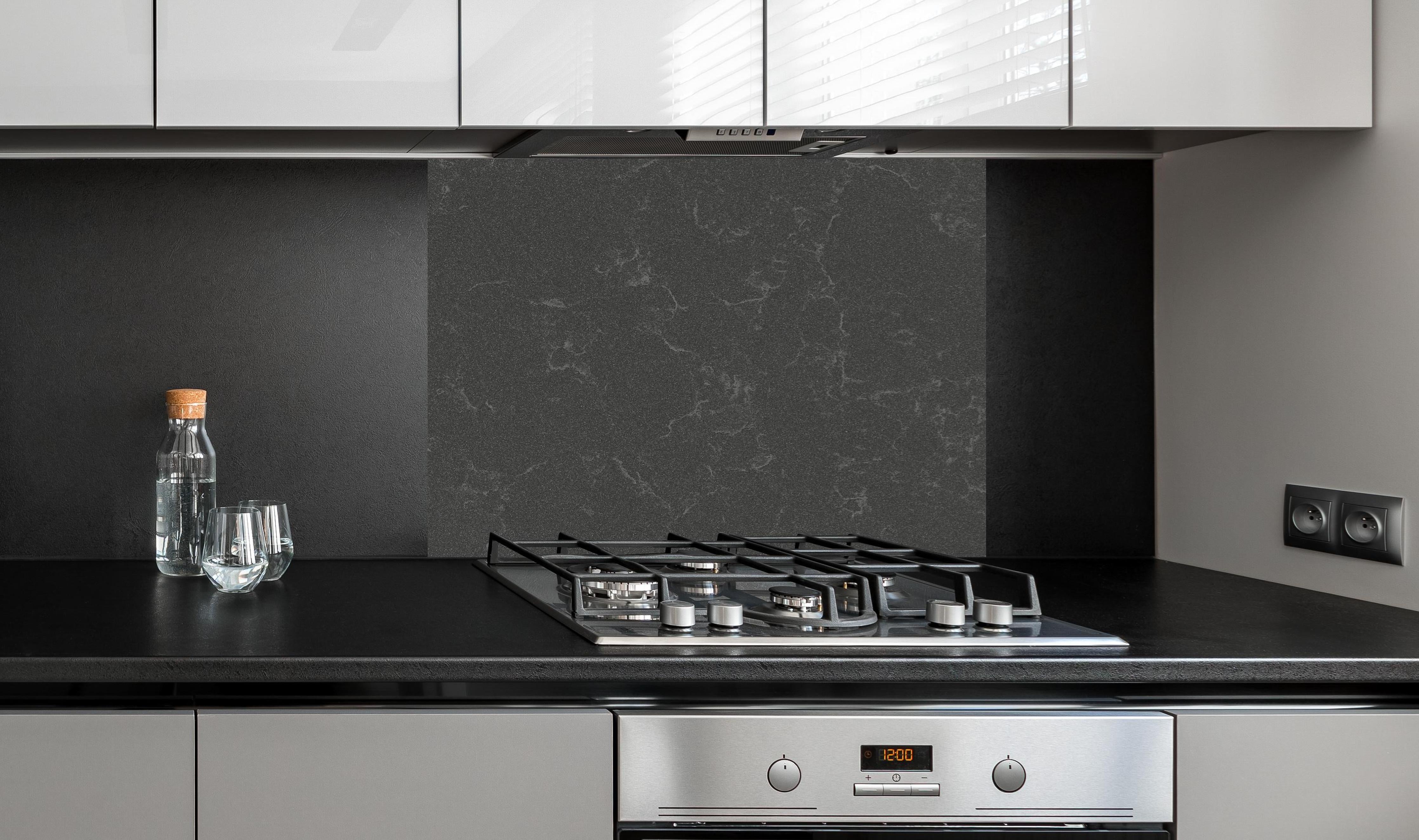 Spritzschutz - Quarz Mineralstone Dark hinter einem Cerankochfeld zwischen Holz-Kochutensilien