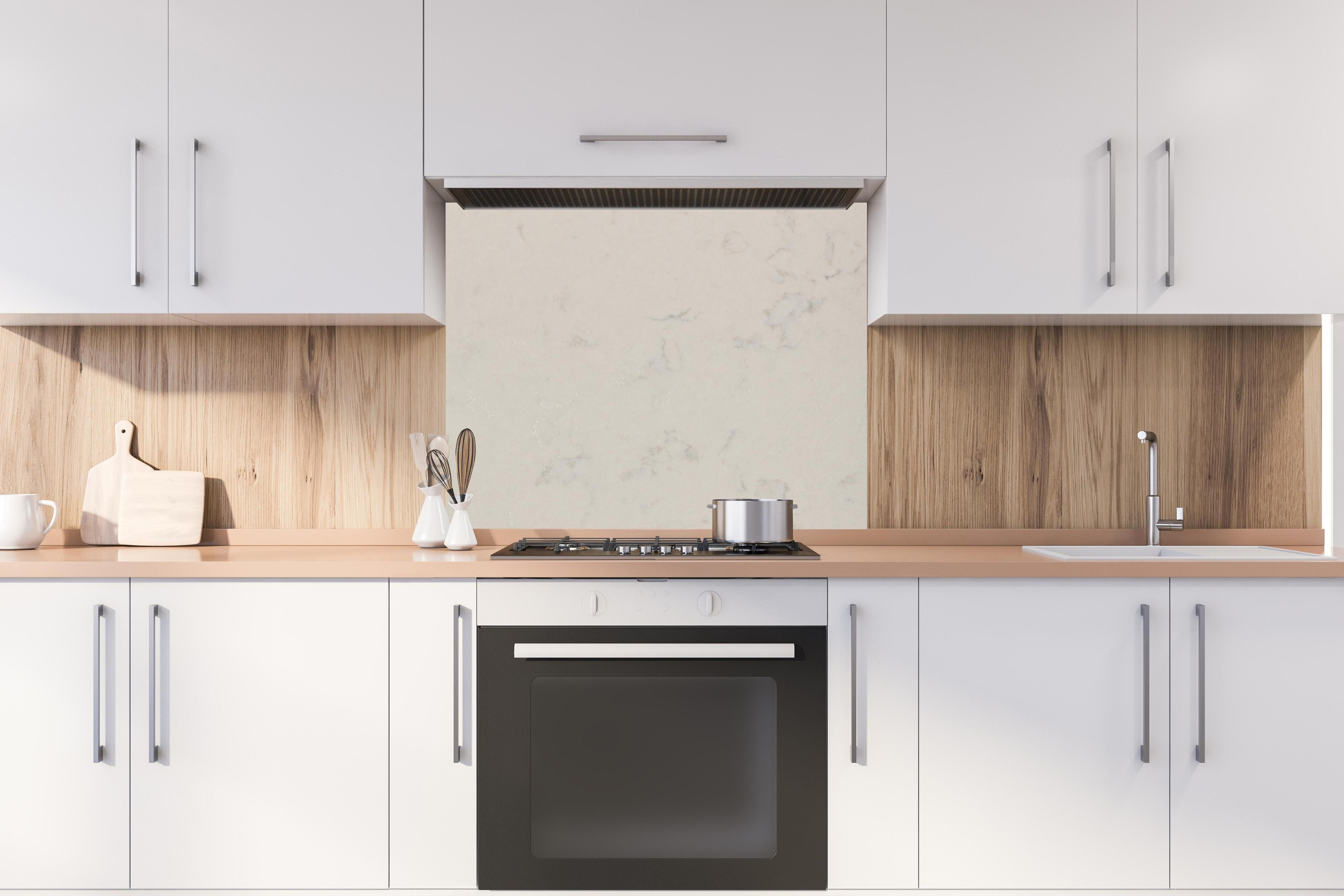 Spritzschutz - Quarz Onyx White hinter einem Cerankochfeld zwischen Holz-Kochutensilien