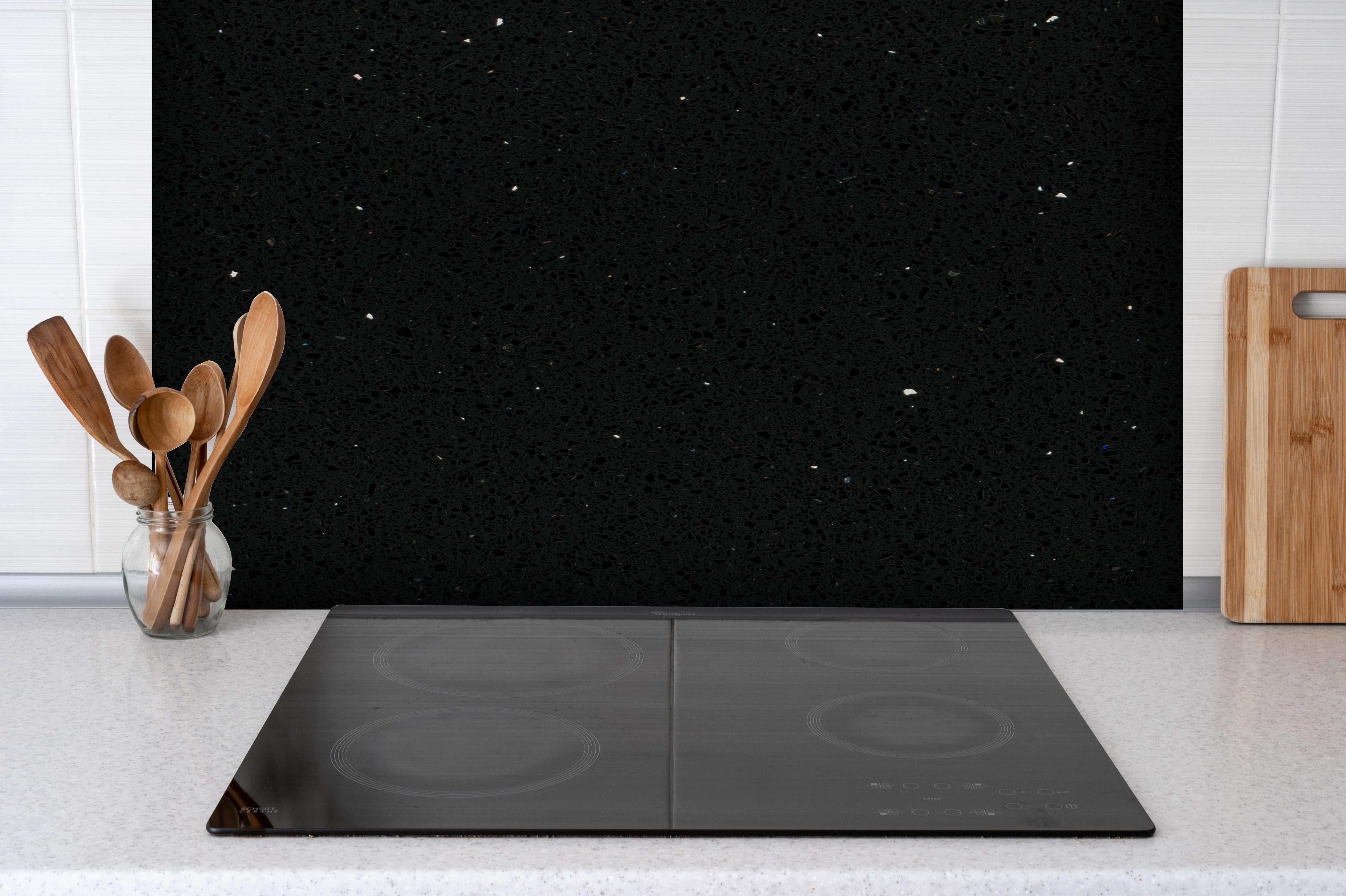 Spritzschutz - Quarz Skydance Black hinter einem Cerankochfeld zwischen Holz-Kochutensilien