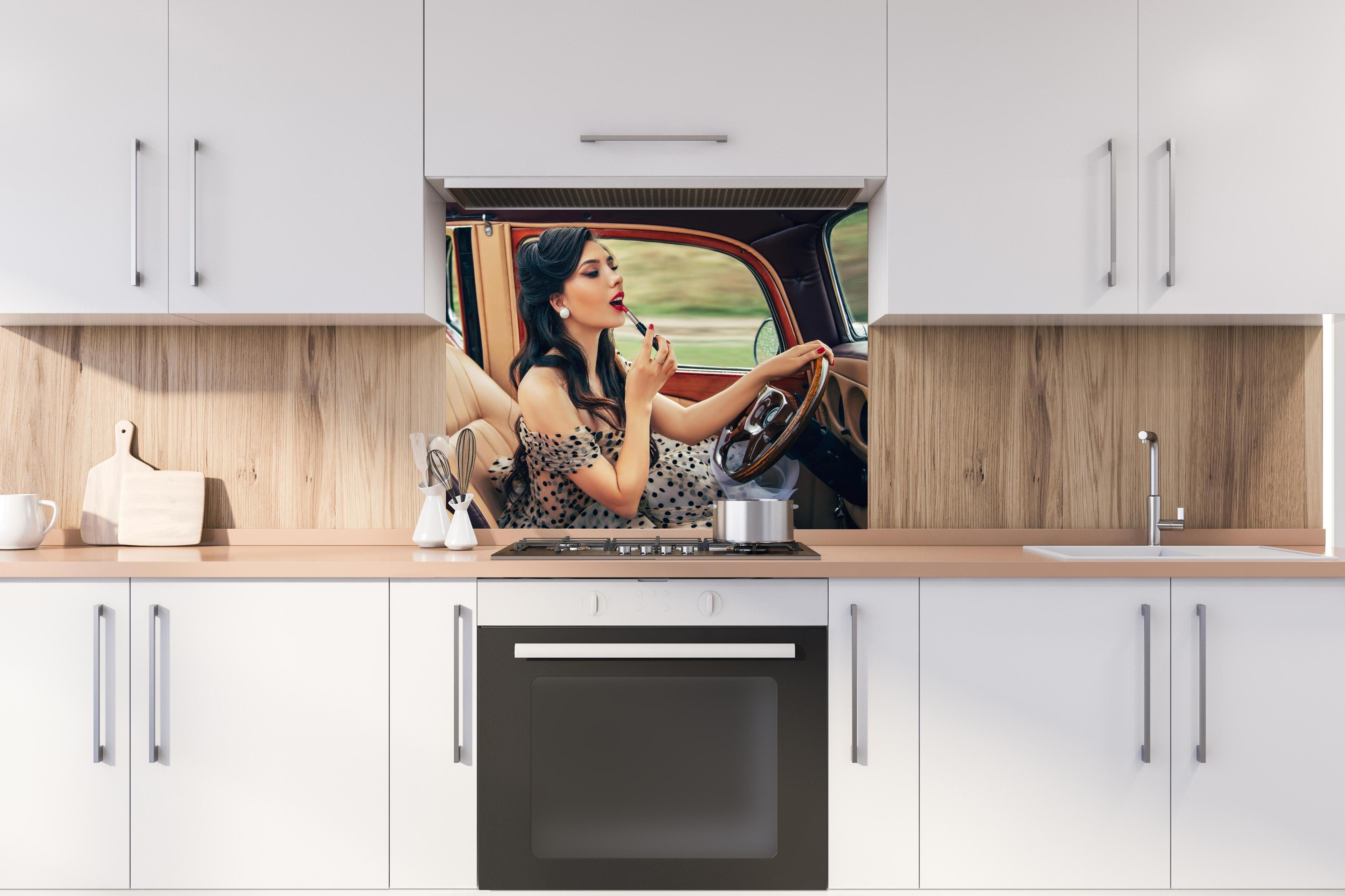 Spritzschutz - Retro Schönheit mit Autolenkrad und Lippenstift hinter einem Cerankochfeld zwischen Holz-Kochutensilien