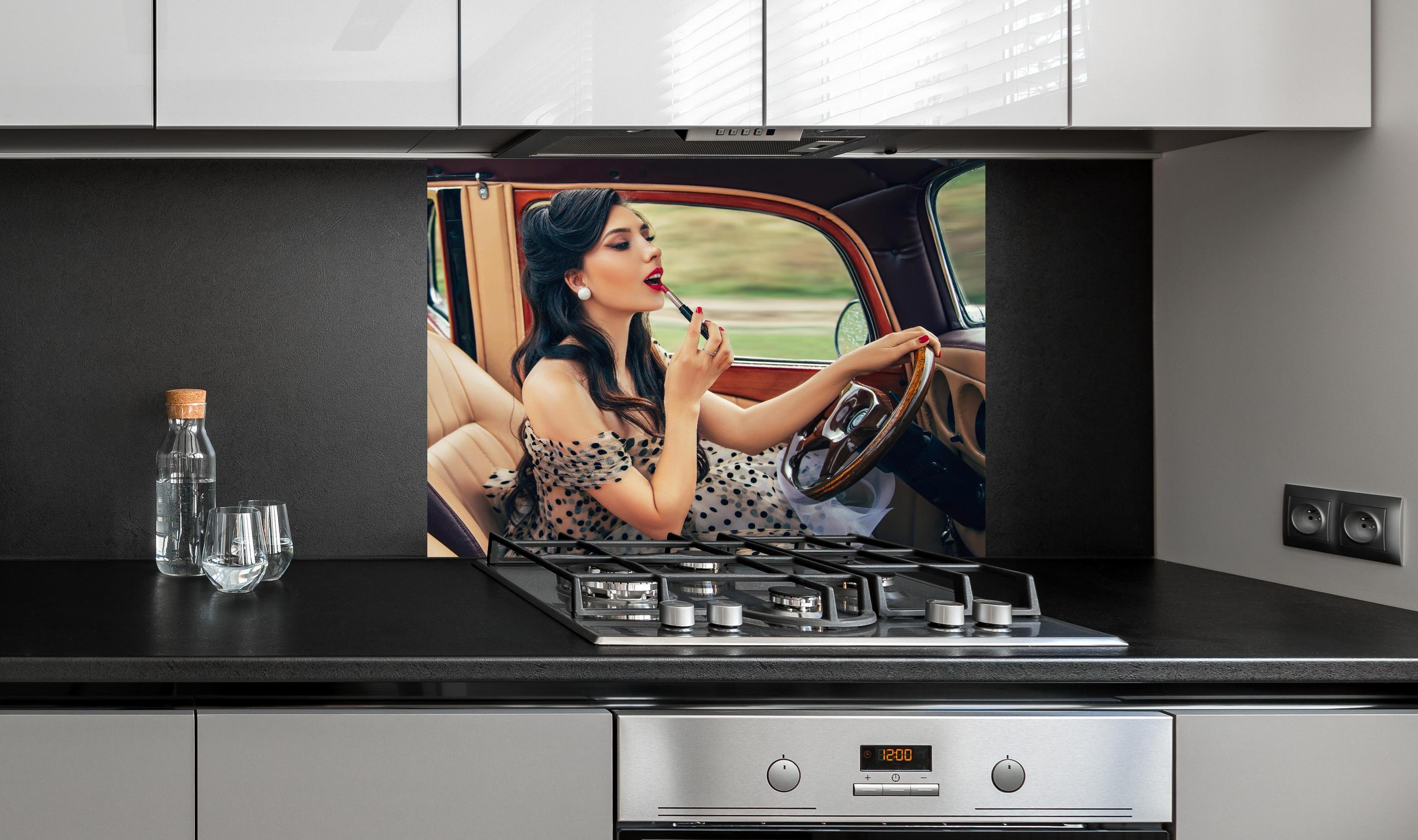 Spritzschutz - Retro Schönheit mit Autolenkrad und Lippenstift hinter einem Cerankochfeld zwischen Holz-Kochutensilien