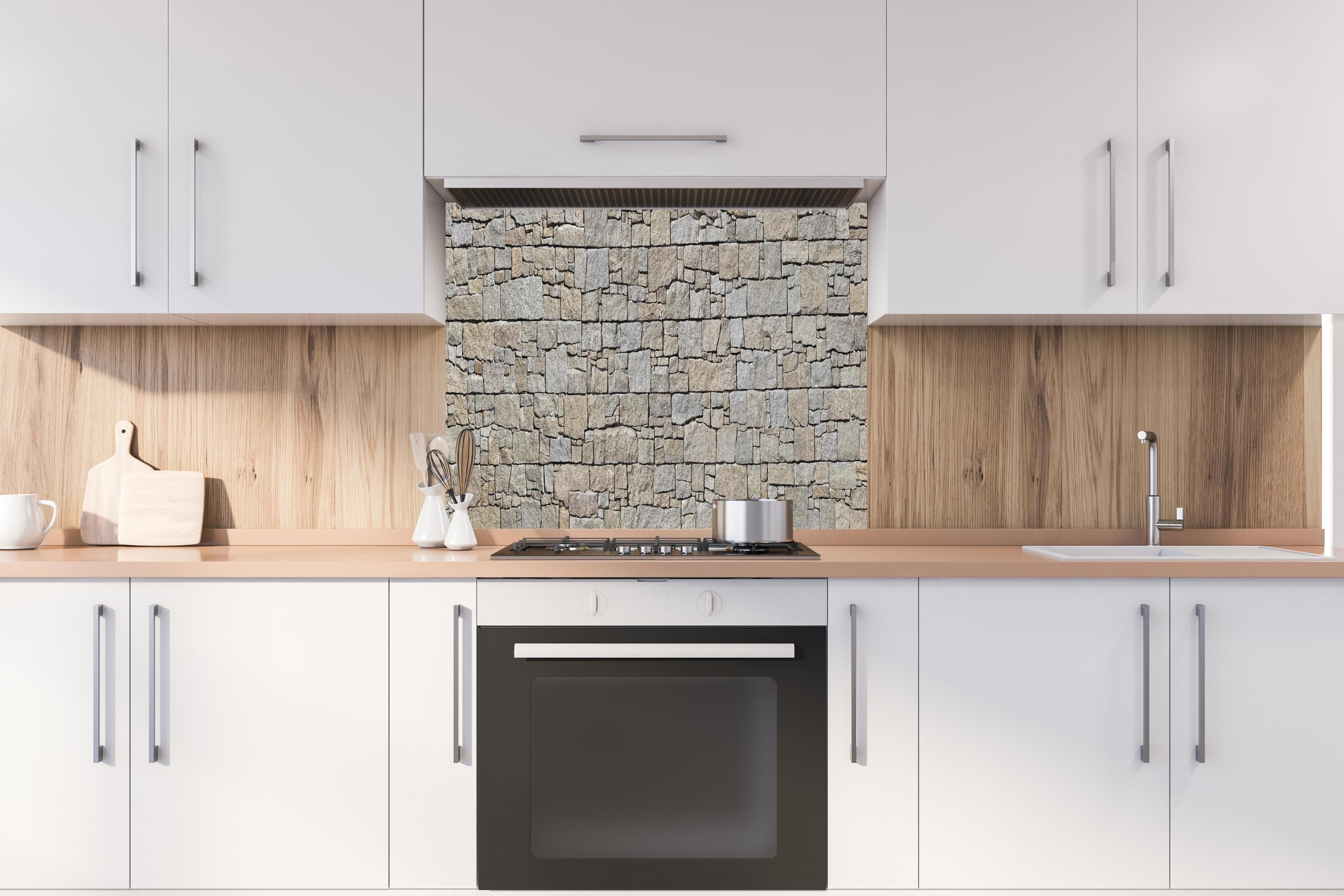 Spritzschutz - Robuste beige Natursteinmauertextur hinter einem Cerankochfeld zwischen Holz-Kochutensilien
