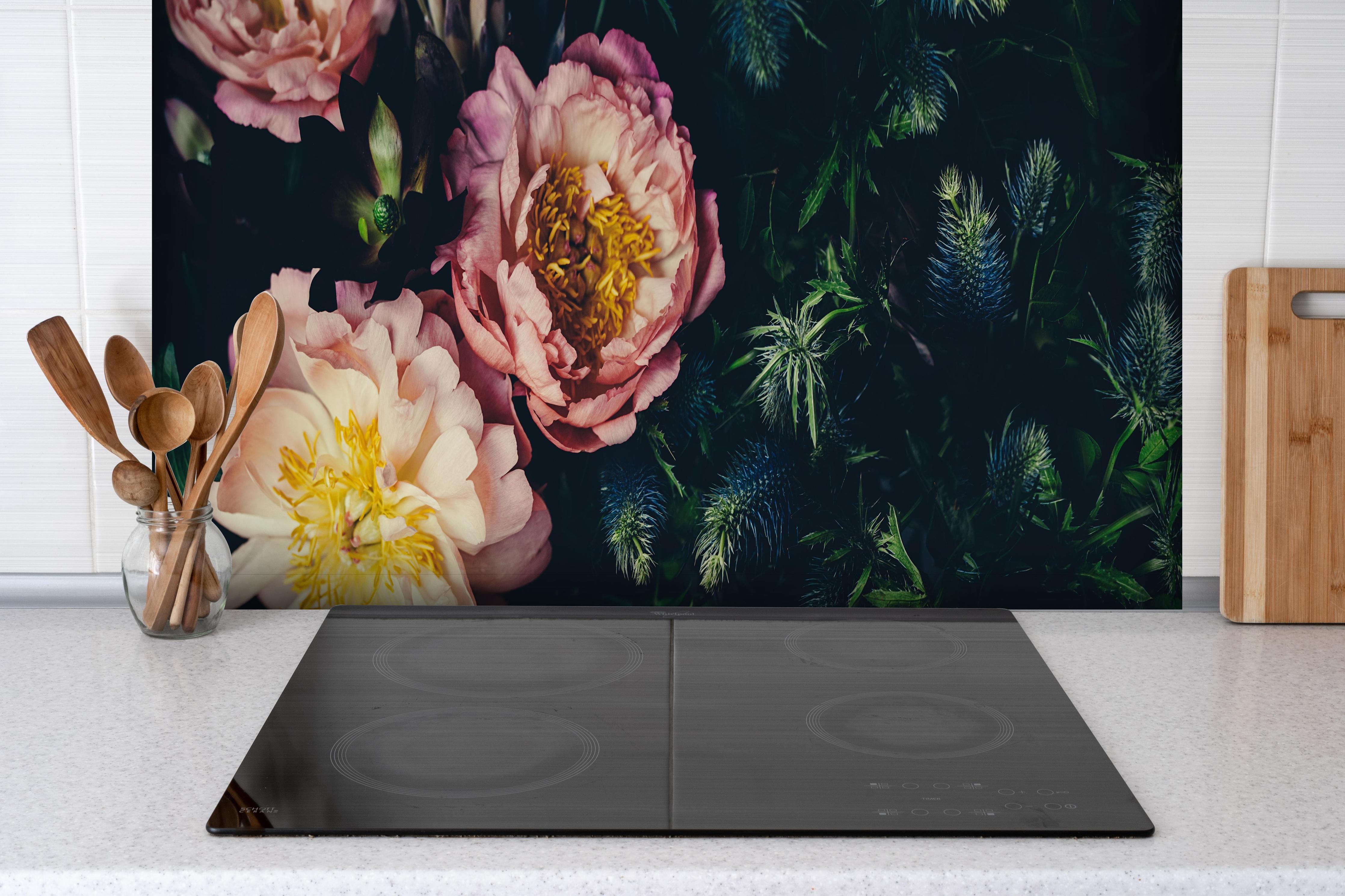 Spritzschutz - Rosa Blüten auf einer Wiese hinter einem Cerankochfeld zwischen Holz-Kochutensilien