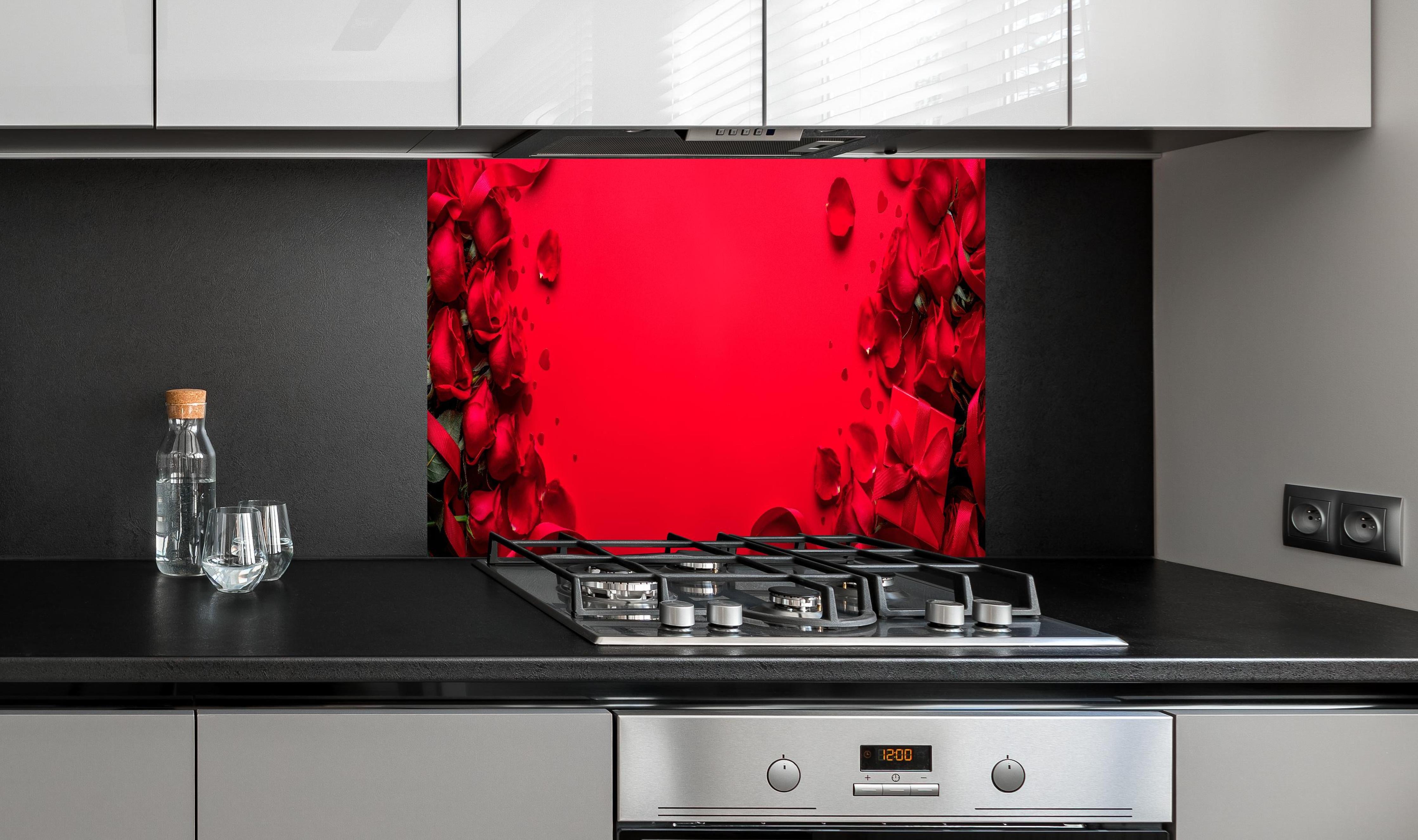 Spritzschutz - Rosengeschenk auf rotem Hintergrund hinter einem Cerankochfeld zwischen Holz-Kochutensilien