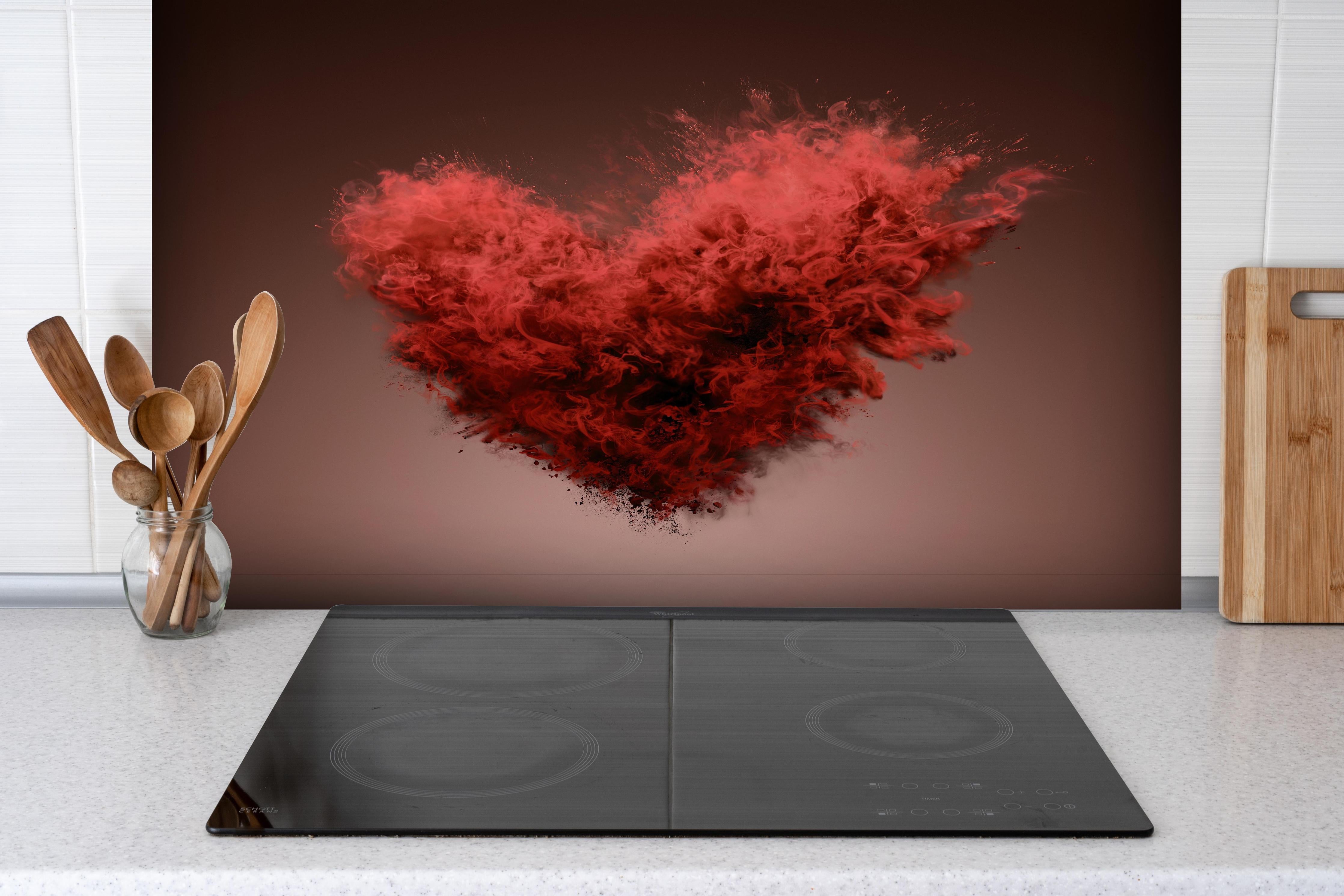 Spritzschutz - Rote Herz-Farbexplosion hinter einem Cerankochfeld zwischen Holz-Kochutensilien