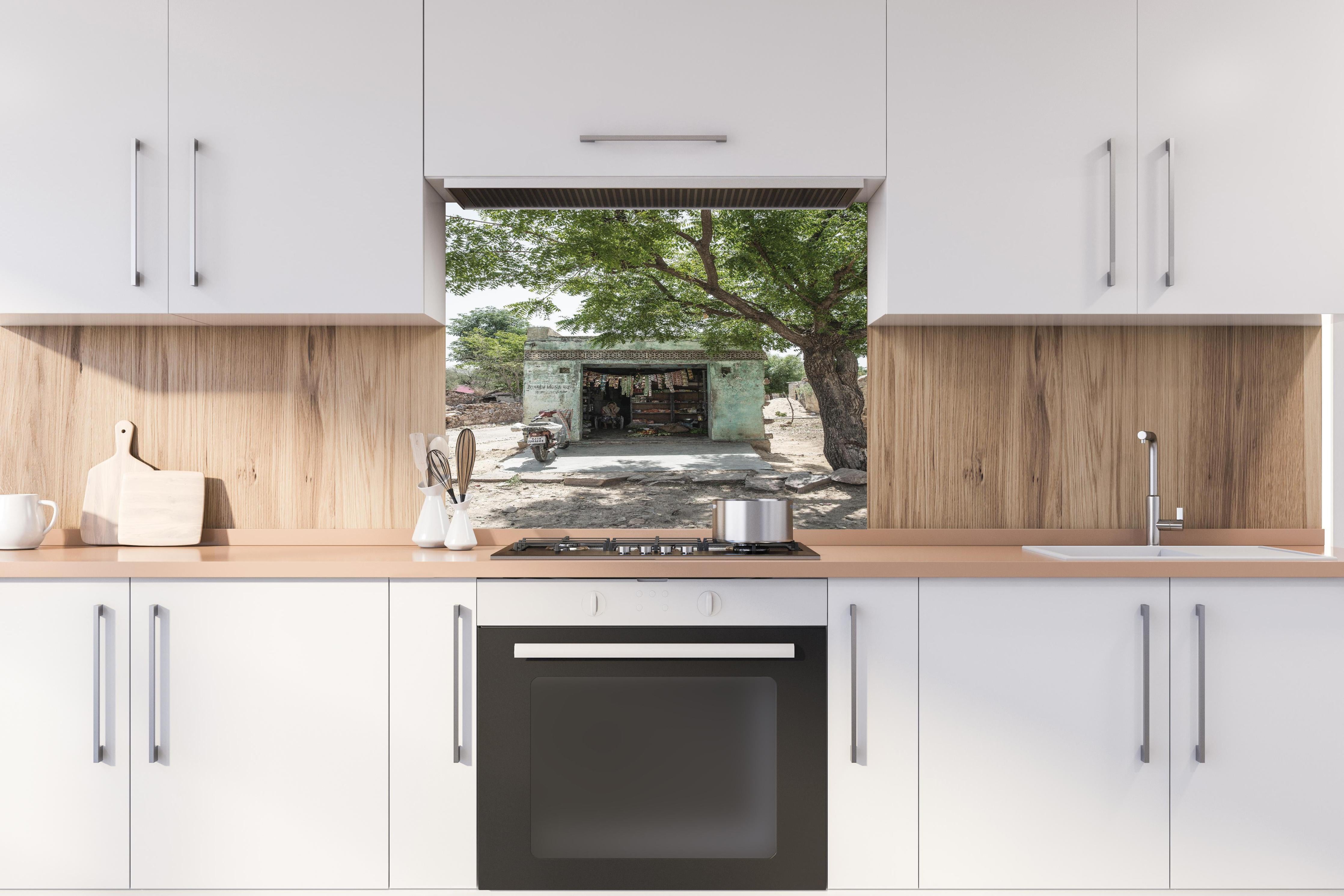 Spritzschutz - Rustikaler Laden unter Bäumen hinter einem Cerankochfeld zwischen Holz-Kochutensilien