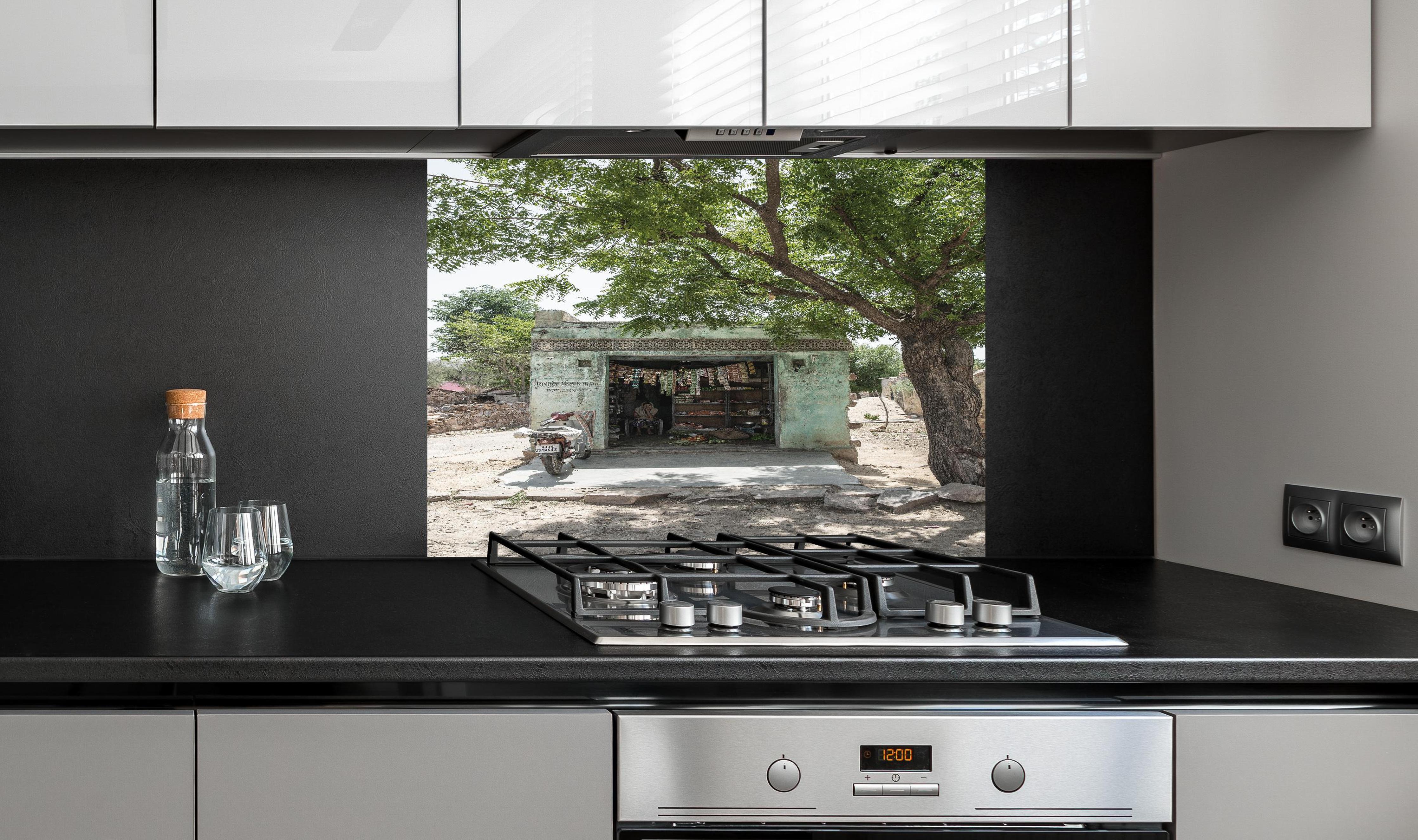 Spritzschutz - Rustikaler Laden unter Bäumen hinter einem Cerankochfeld zwischen Holz-Kochutensilien