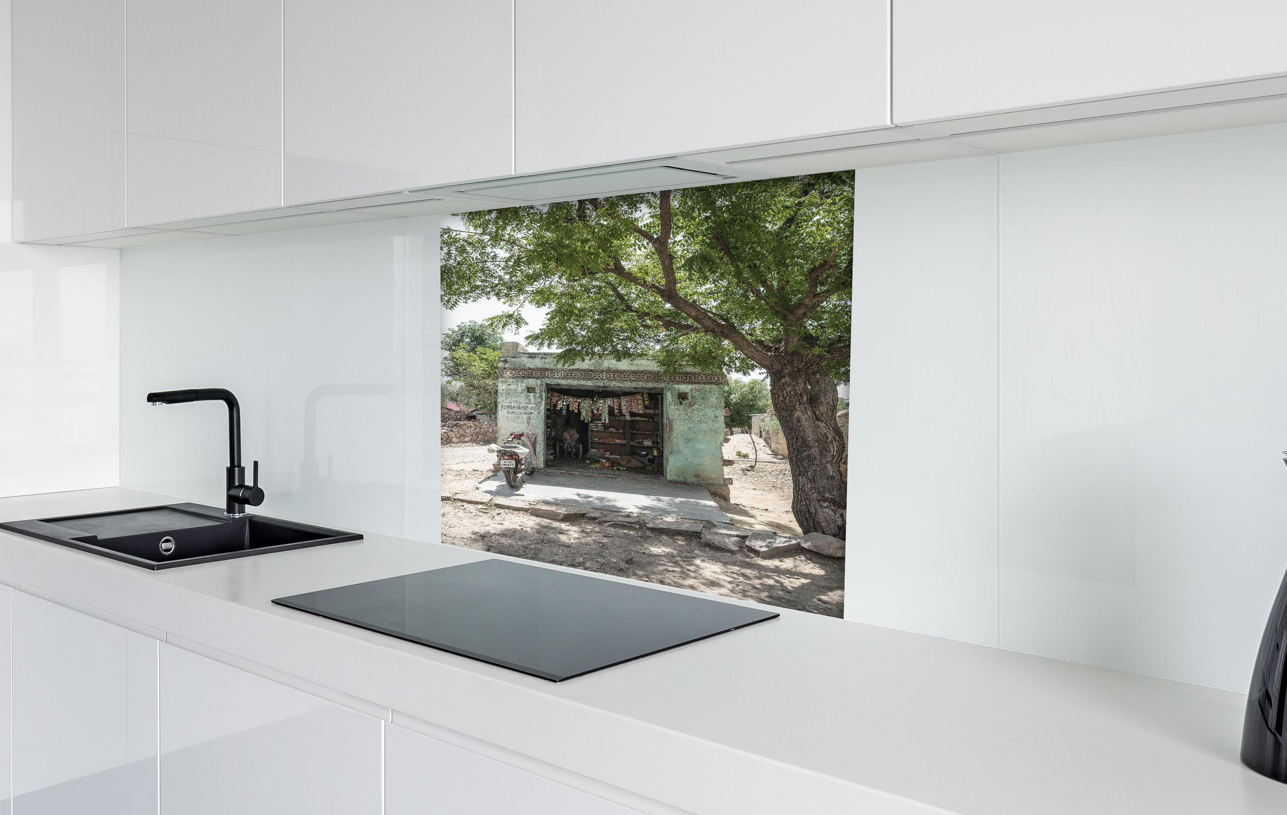 Spritzschutz - Rustikaler Laden unter Bäumen hinter einem Cerankochfeld zwischen Holz-Kochutensilien