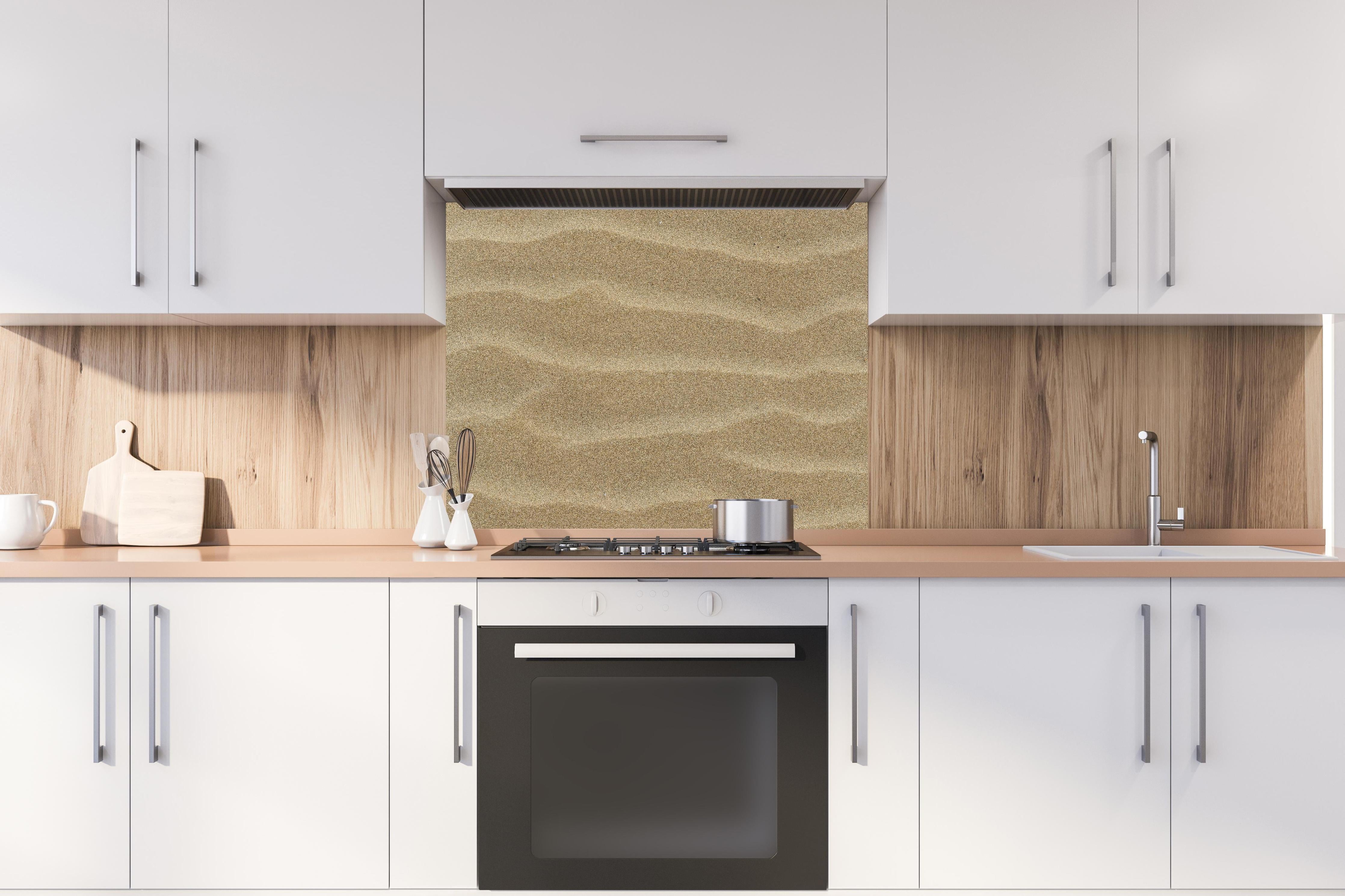 Spritzschutz - Sandstrand hinter einem Cerankochfeld zwischen Holz-Kochutensilien