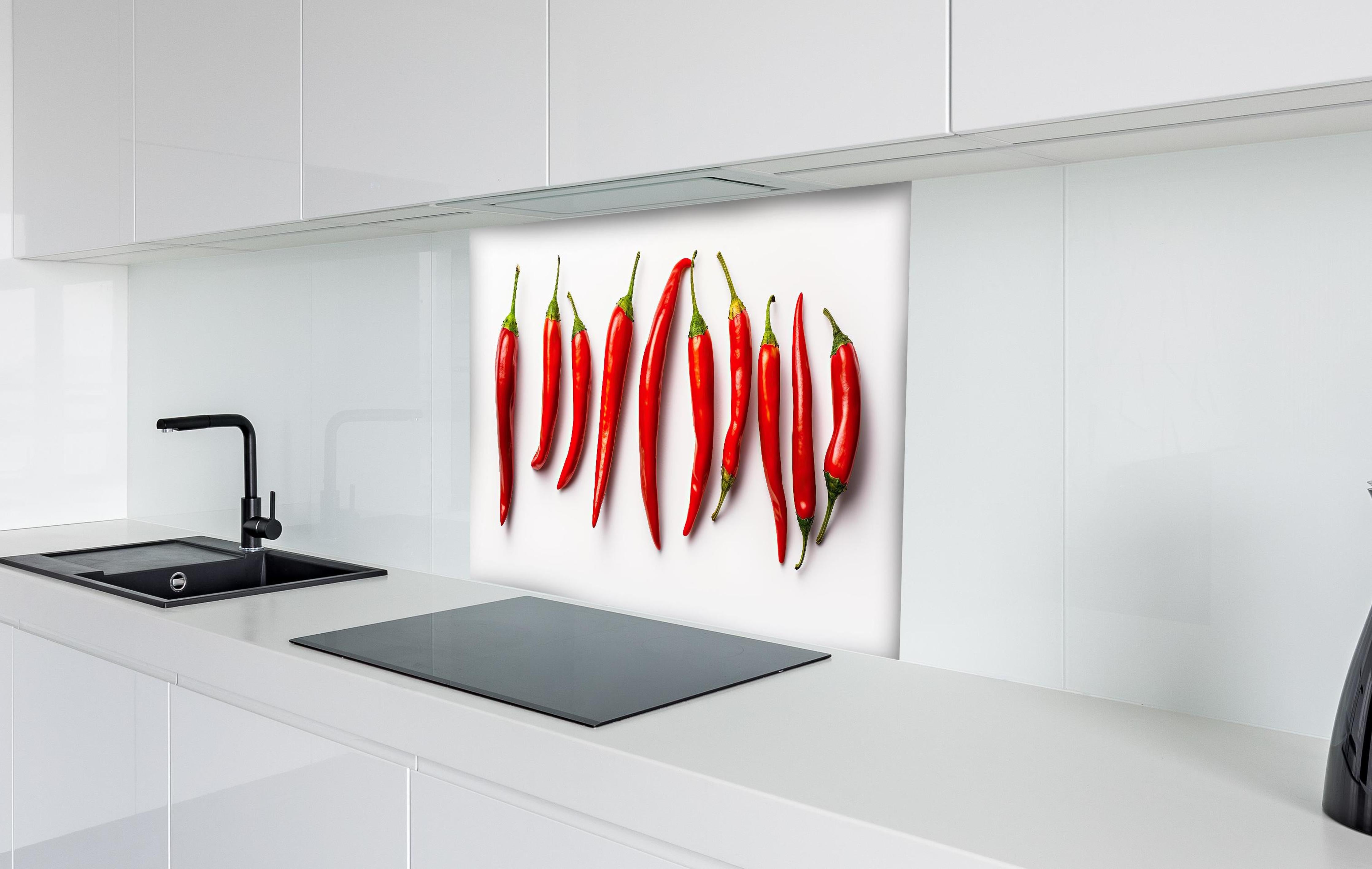 Spritzschutz - Scharfe Rote Chili Schoten im Überblick hinter einem Cerankochfeld zwischen Holz-Kochutensilien