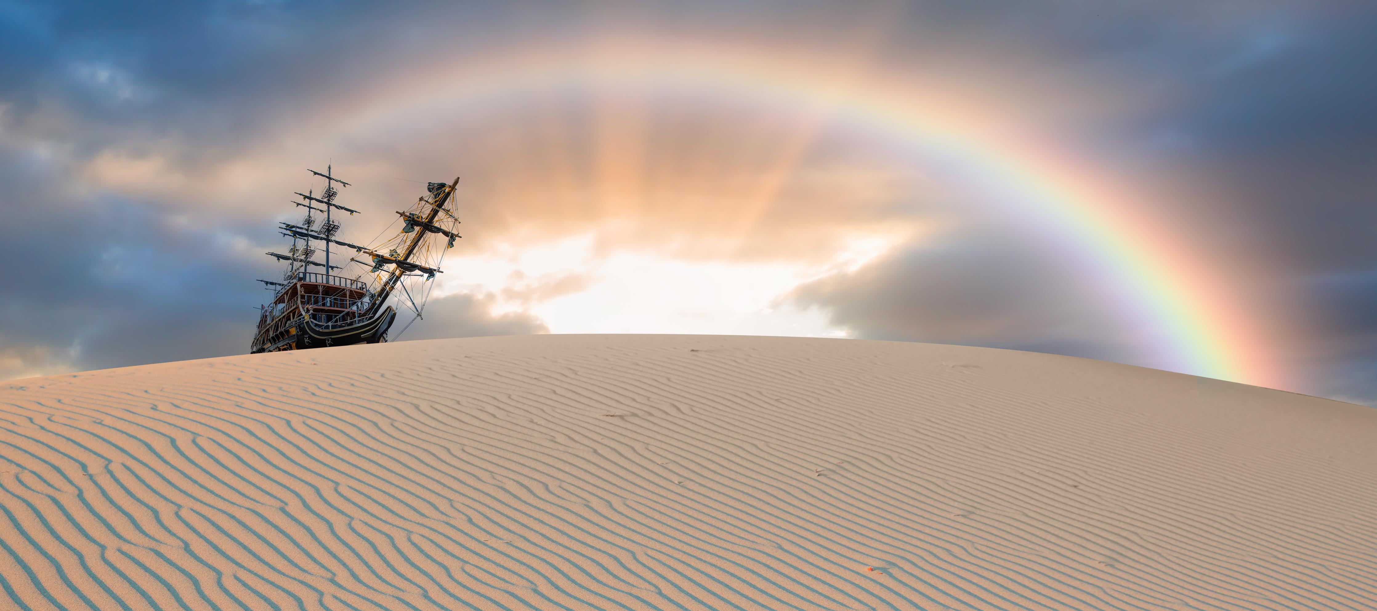 Spritzschutz-Schiff in Wüste mit Regenbogen bei Sonnenuntergang