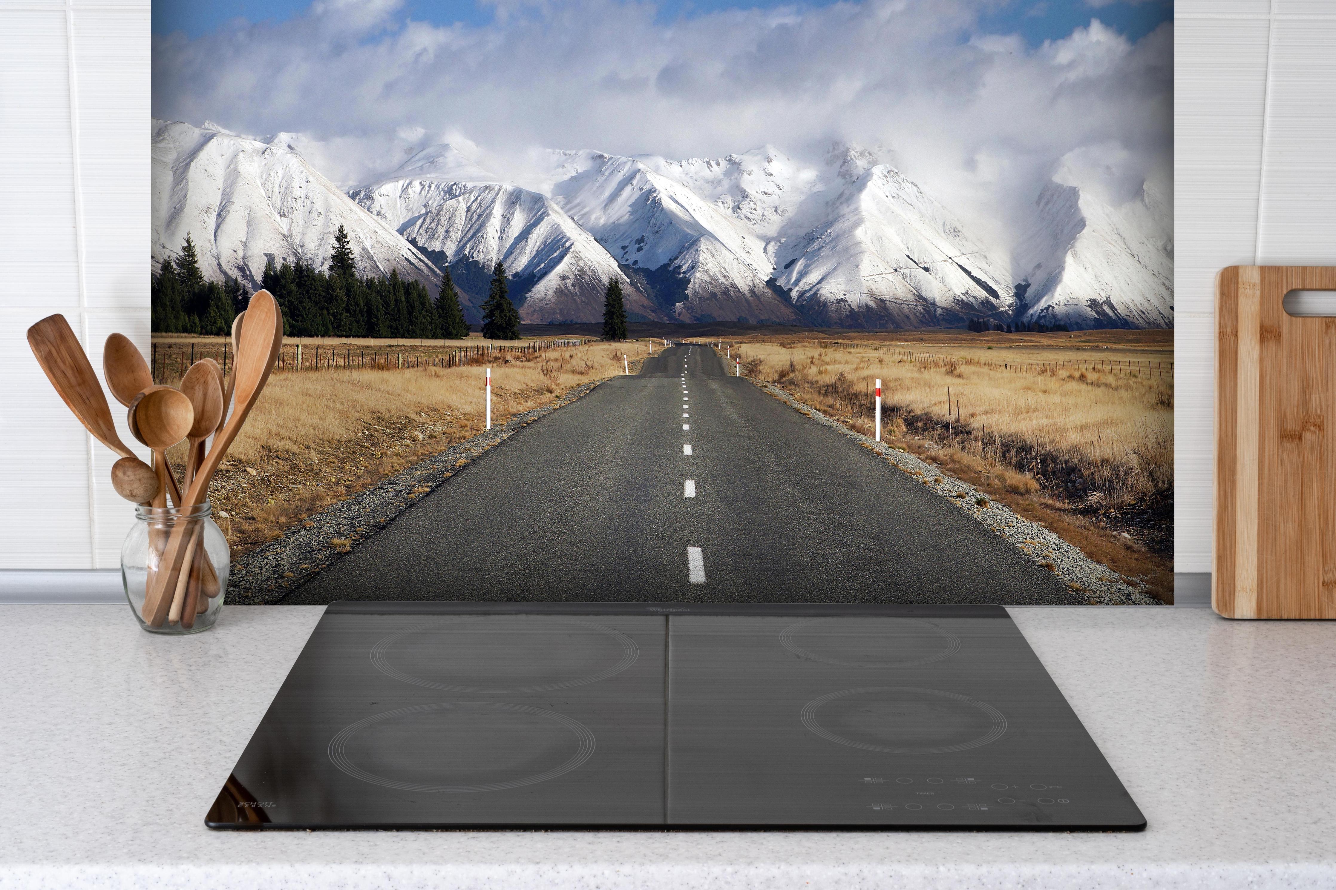 Spritzschutz - Schneebedeckte Bergspitzen im Winter hinter einem Cerankochfeld zwischen Holz-Kochutensilien