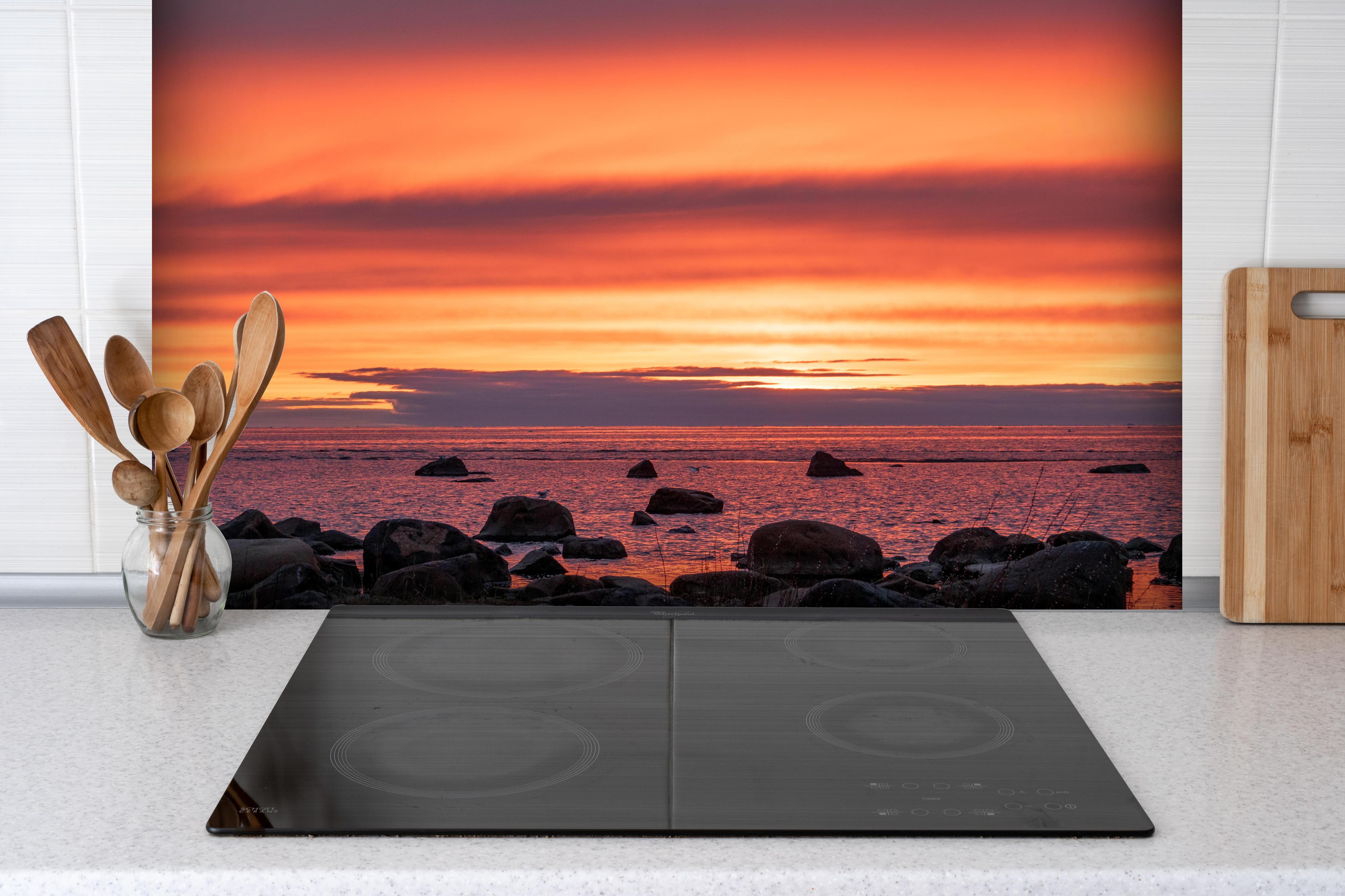Spritzschutz - Schöner Sonnenuntergang am Meer hinter einem Cerankochfeld zwischen Holz-Kochutensilien