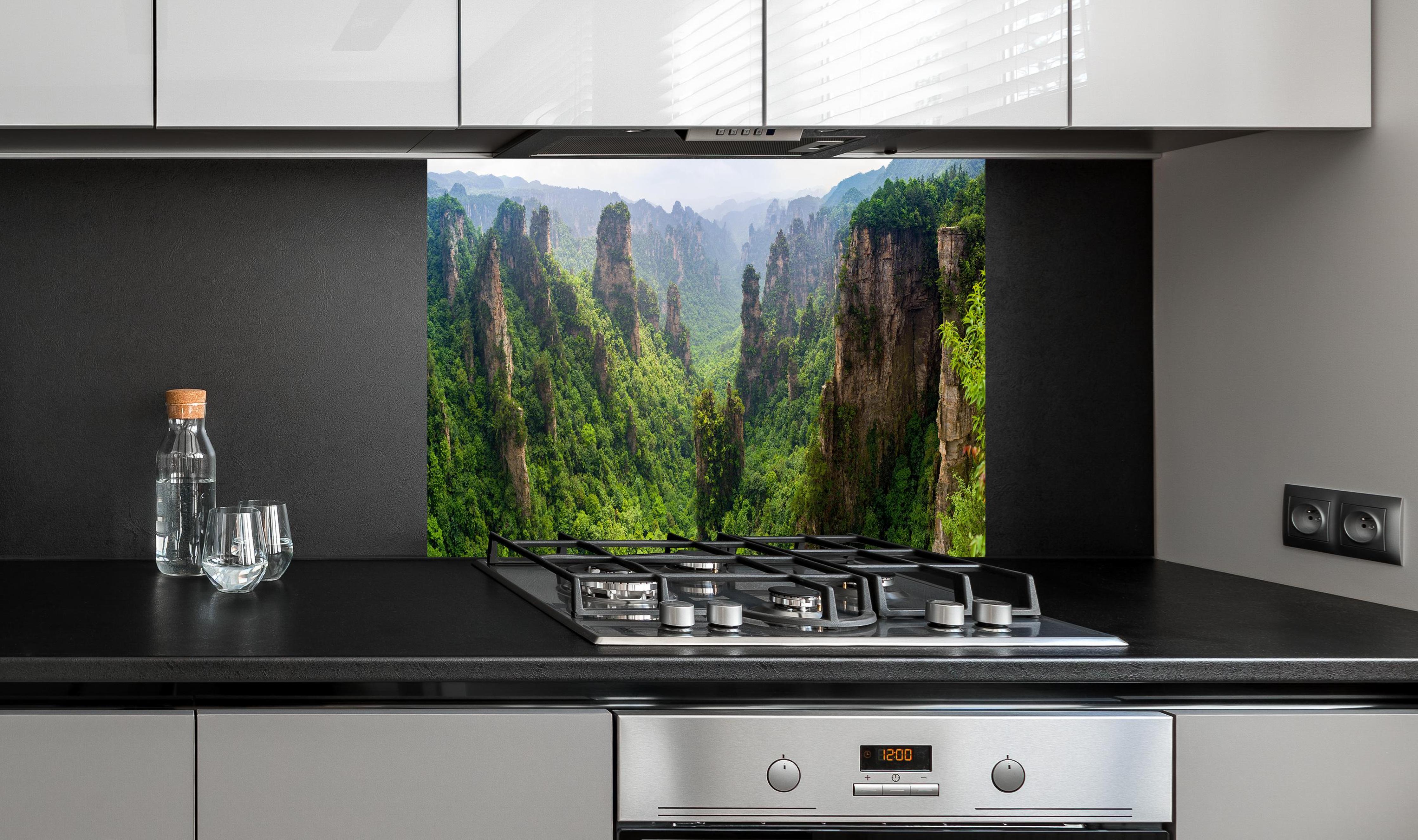 Spritzschutz - Schönes Panorama der Karstberge hinter einem Cerankochfeld zwischen Holz-Kochutensilien