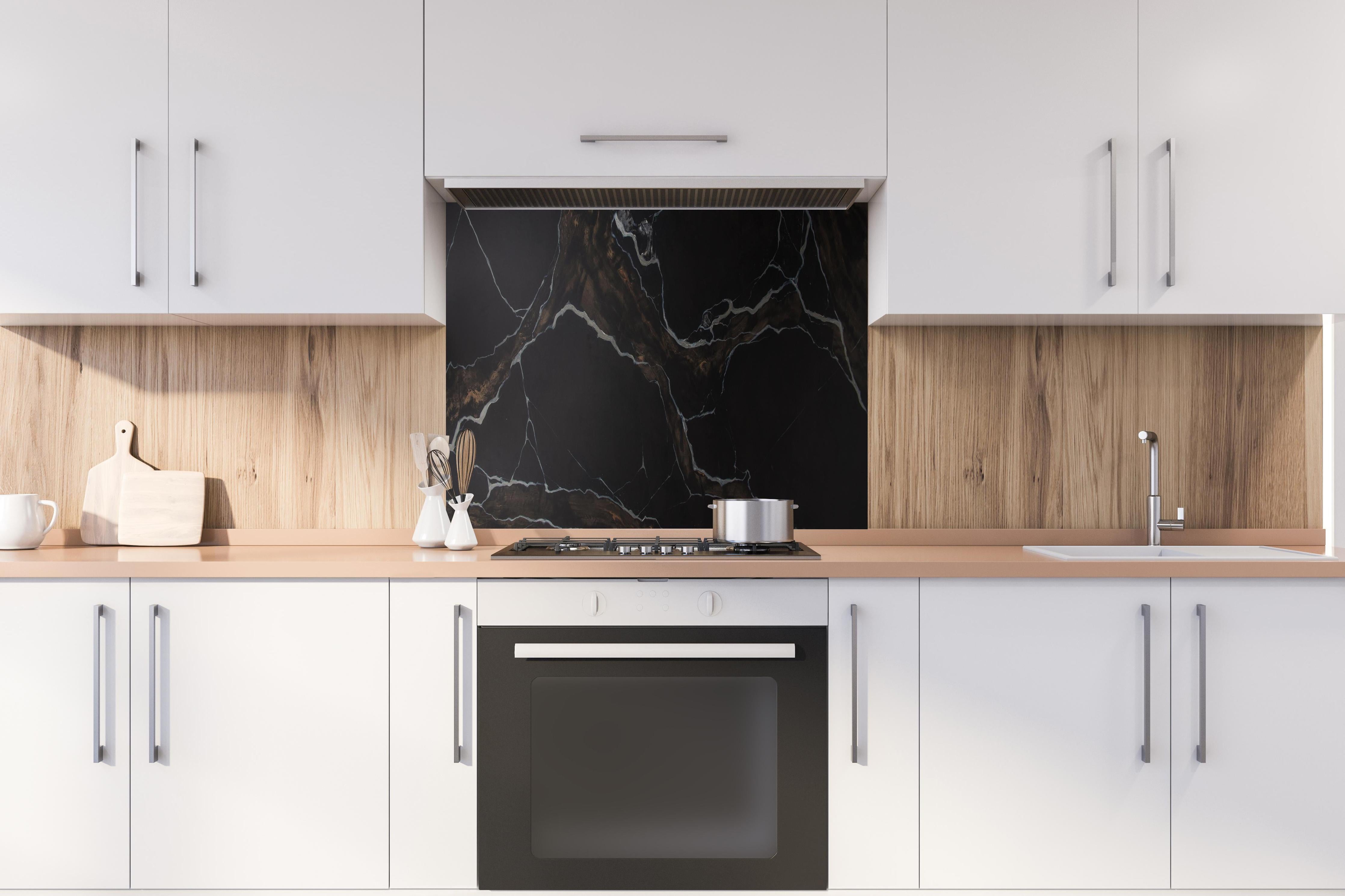 Spritzschutz - Schwarz-brauner Marmor hinter einem Cerankochfeld zwischen Holz-Kochutensilien