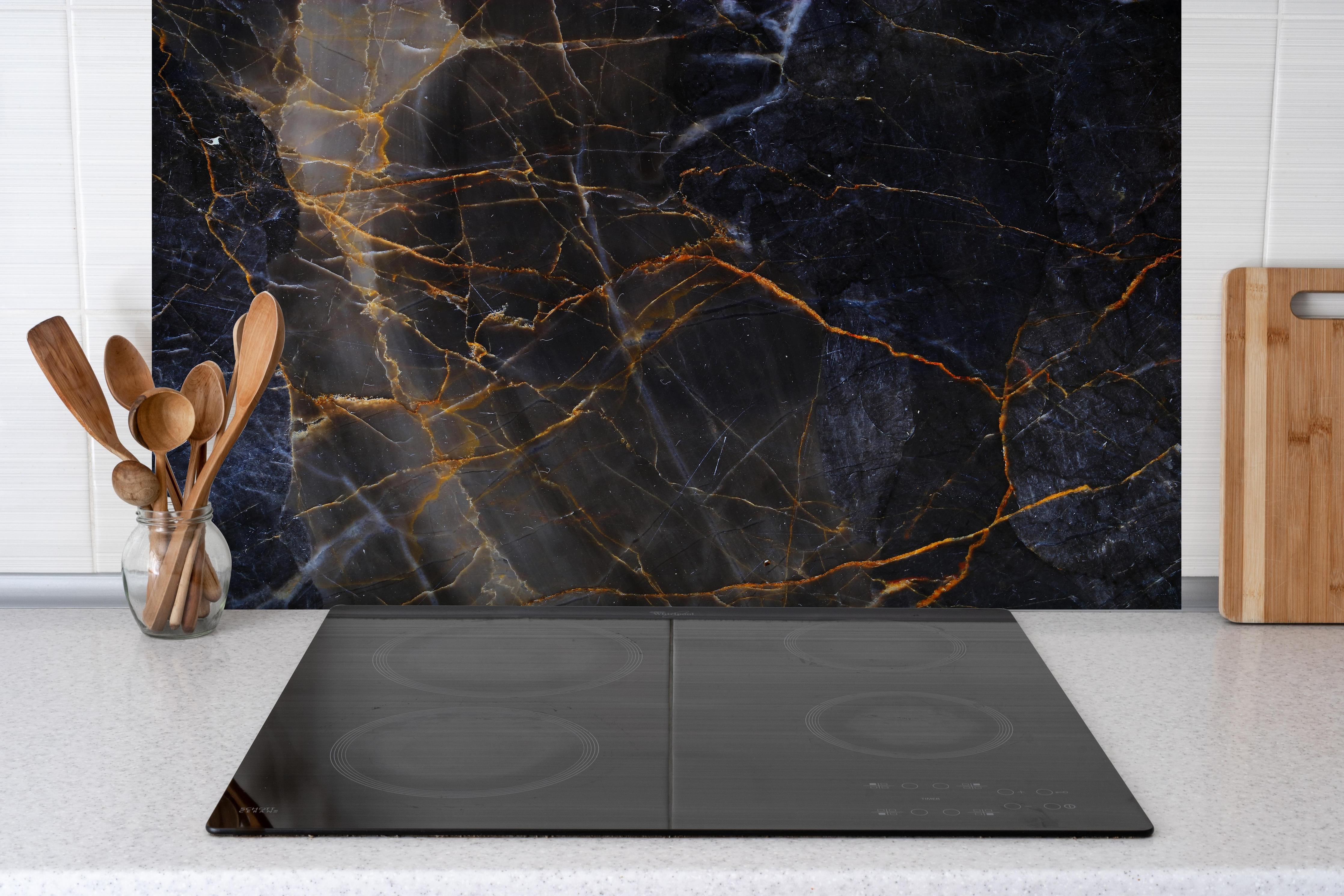 Spritzschutz - Schwarz und braune Marmor Textur aus Russland hinter einem Cerankochfeld zwischen Holz-Kochutensilien